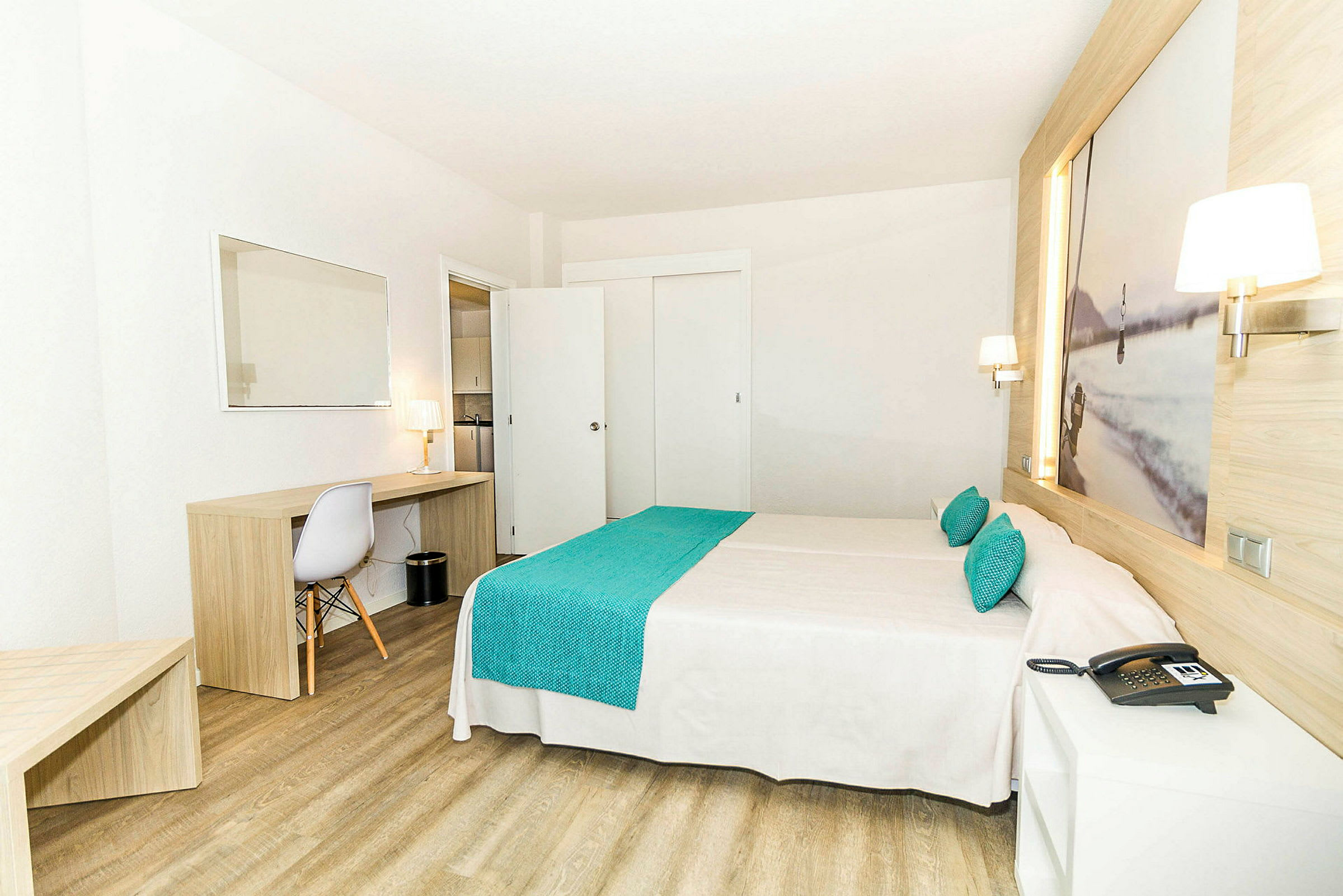 Et hotelværelse med en dobbeltseng, træmøbler og en arbejdsplads med en stol og en lampe. (AI-genereret tekst)