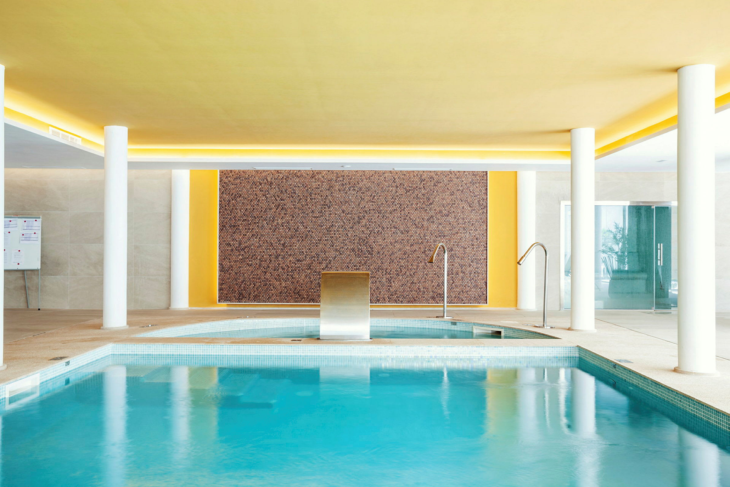 Indendørs pool med springvand og vægdekoration. (AI-genereret tekst)
