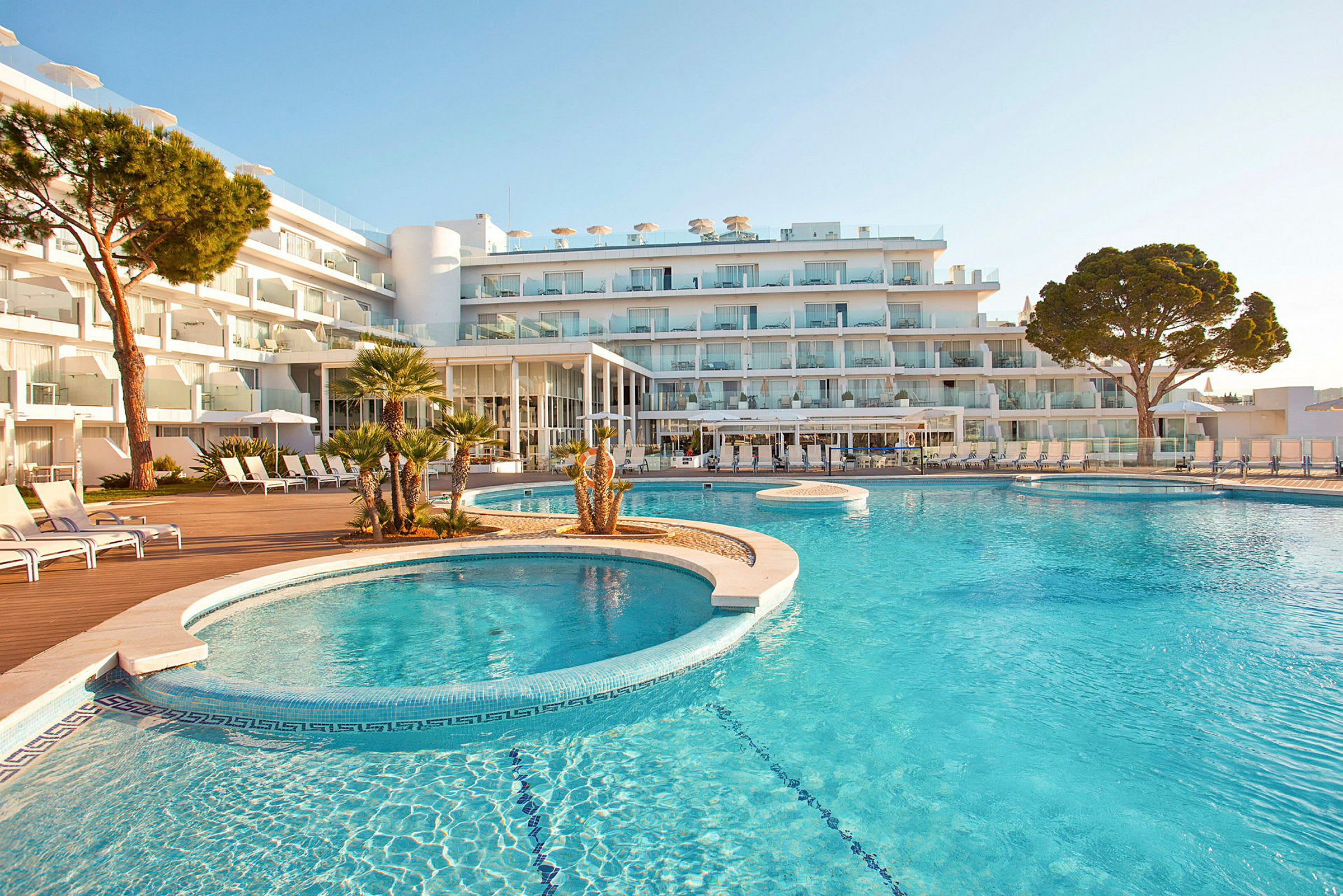 Udendørs pool foran et moderne hotel med flere etager. (AI-genereret tekst)