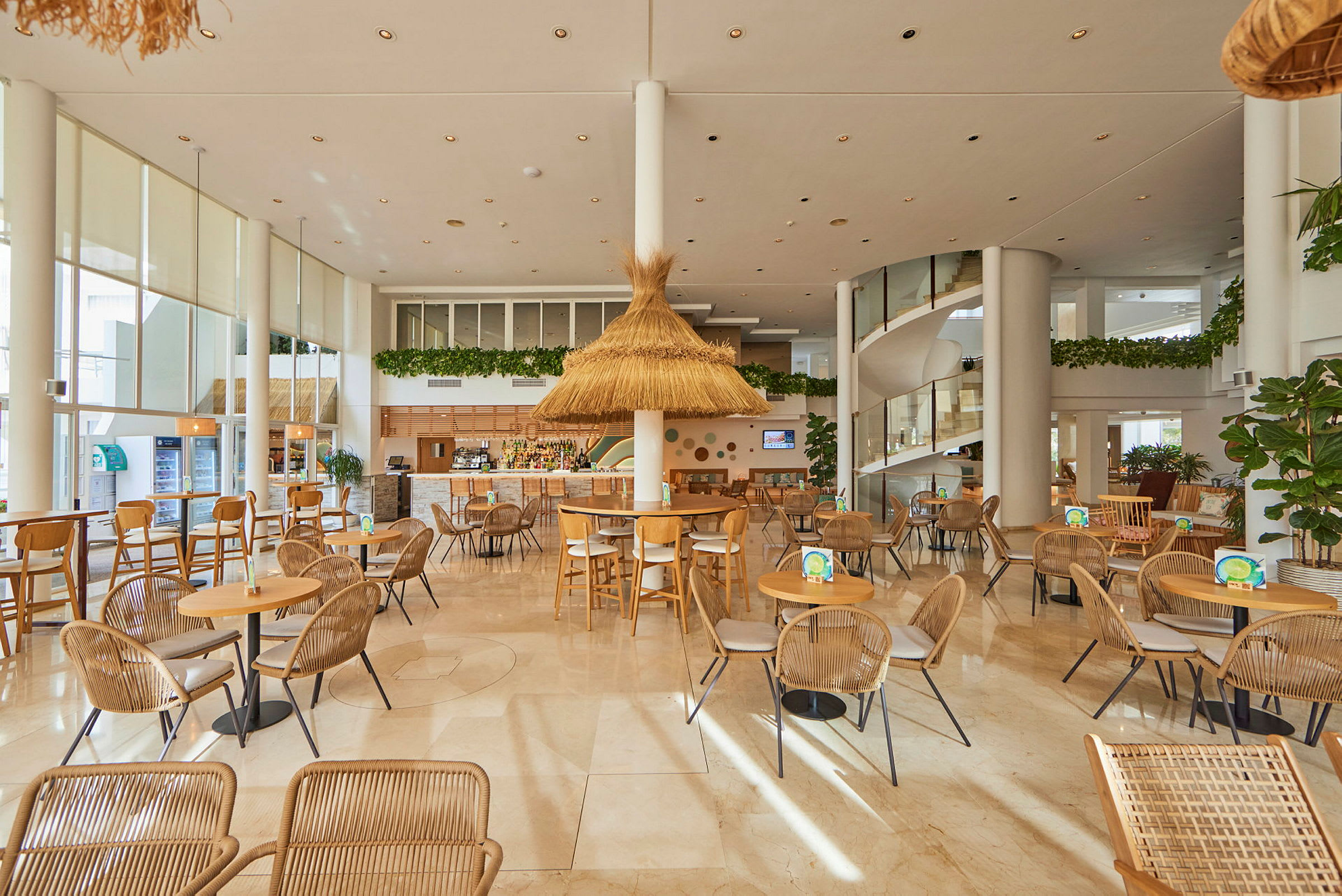 Interiørbillede af en rummelig, lys restaurant med træborde, flettede stole og planteudsmykning. (AI-genereret tekst)