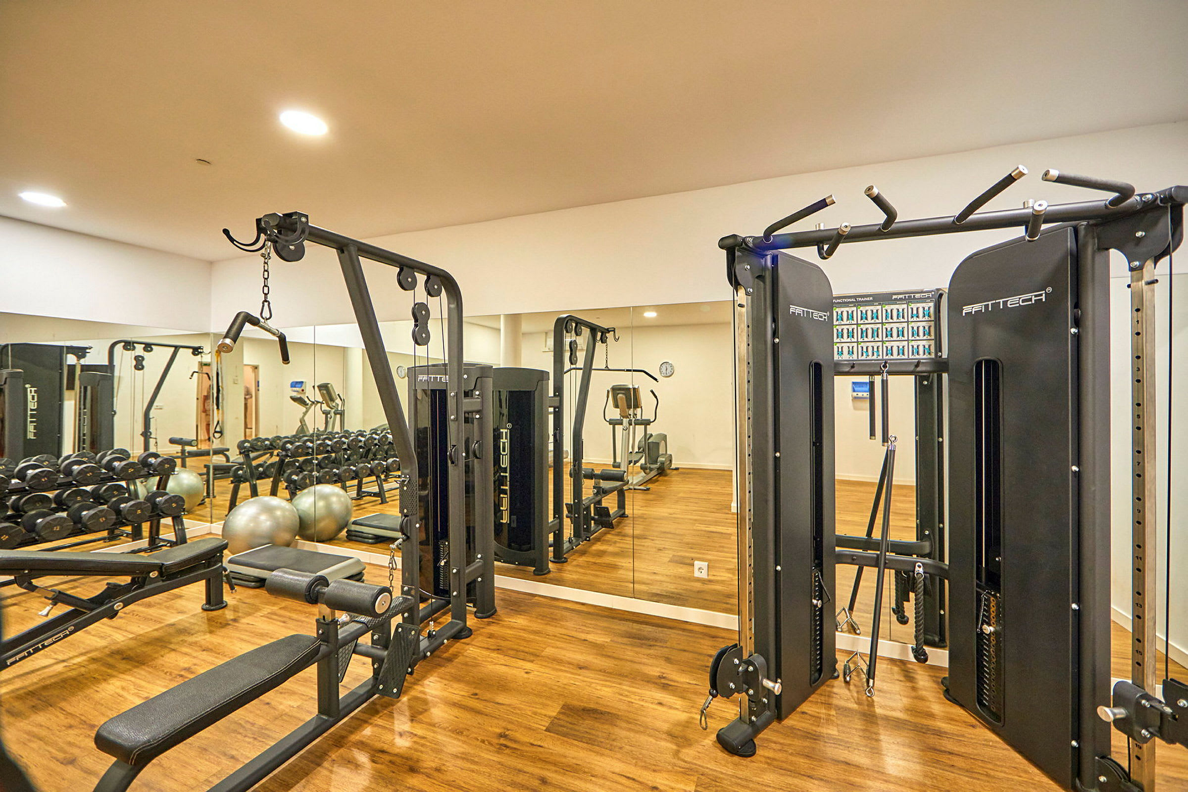 Fitnesscenter med træningsudstyr og spejlbeklædt væg. (AI-genereret tekst)