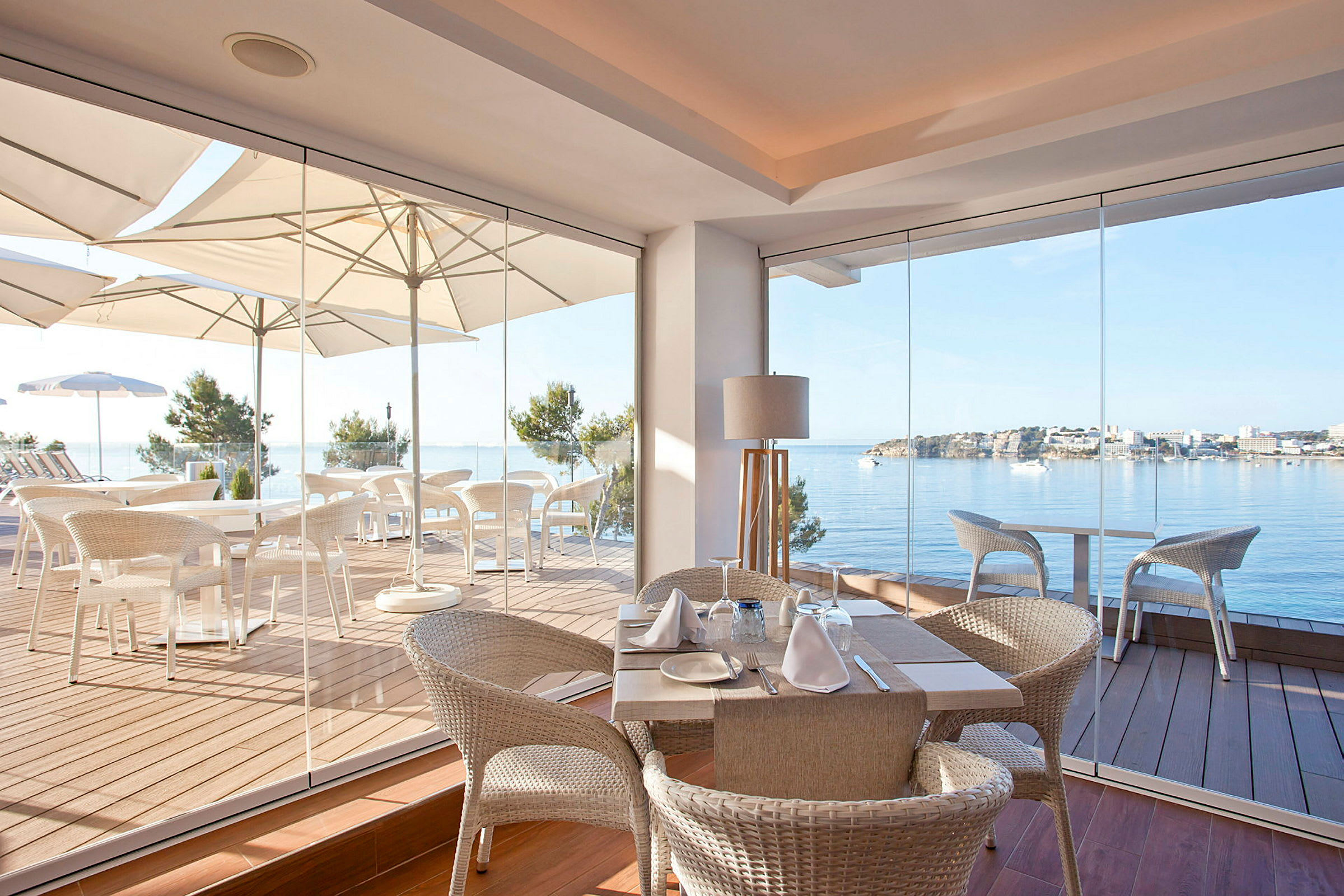 Billede af en restaurant med glasvægge og udsigt over en havbugt. (AI-genereret tekst)