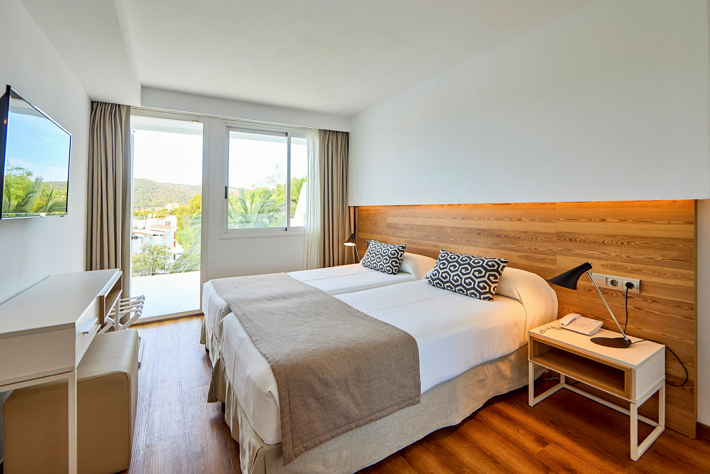 Hotelværelse med to enkeltsenge, en trævægpanel og et vindue med udsigt. (AI-genereret tekst)