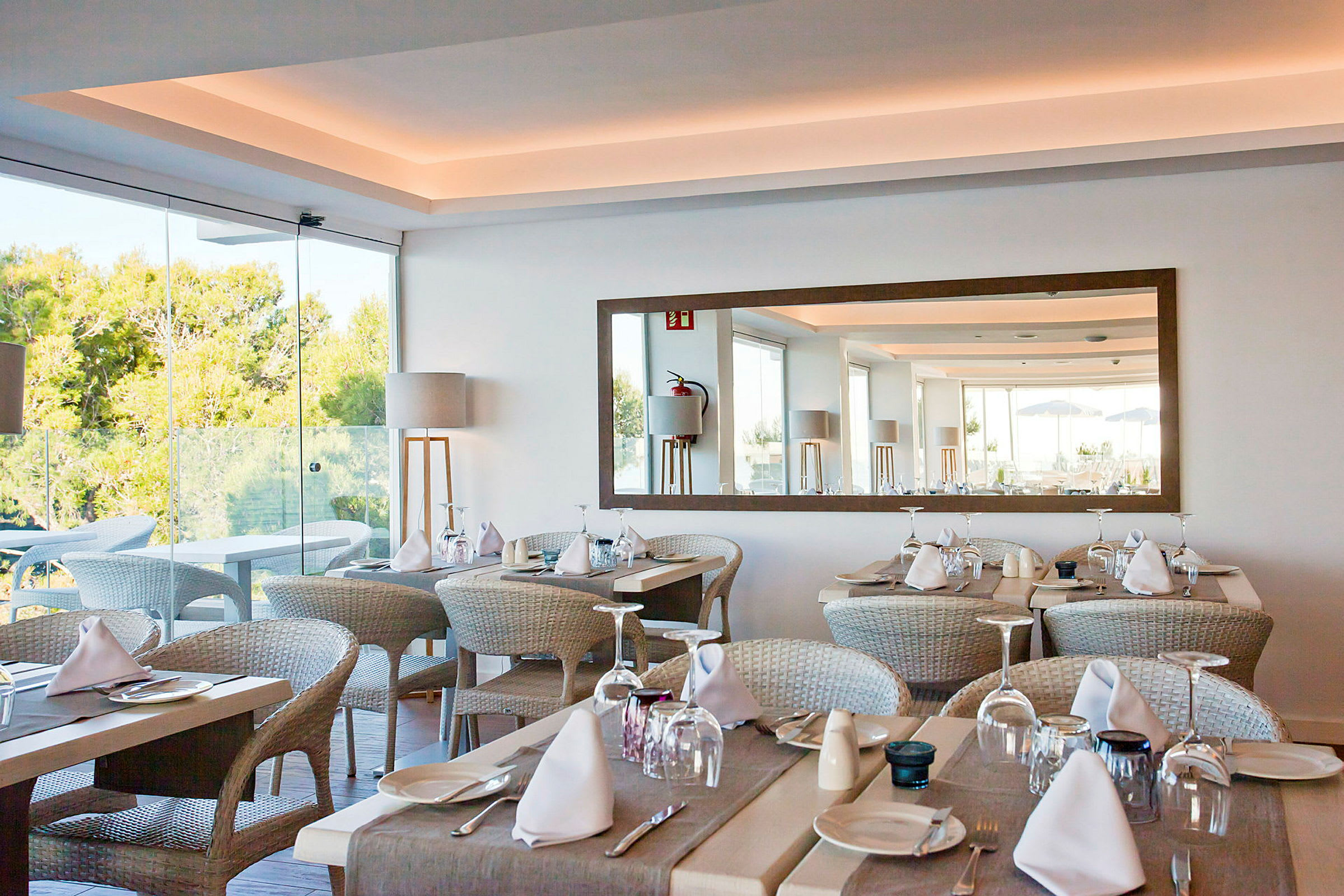 En elegant restaurant med dækkede borde og udsigt til grønne områder. (AI-genereret tekst)