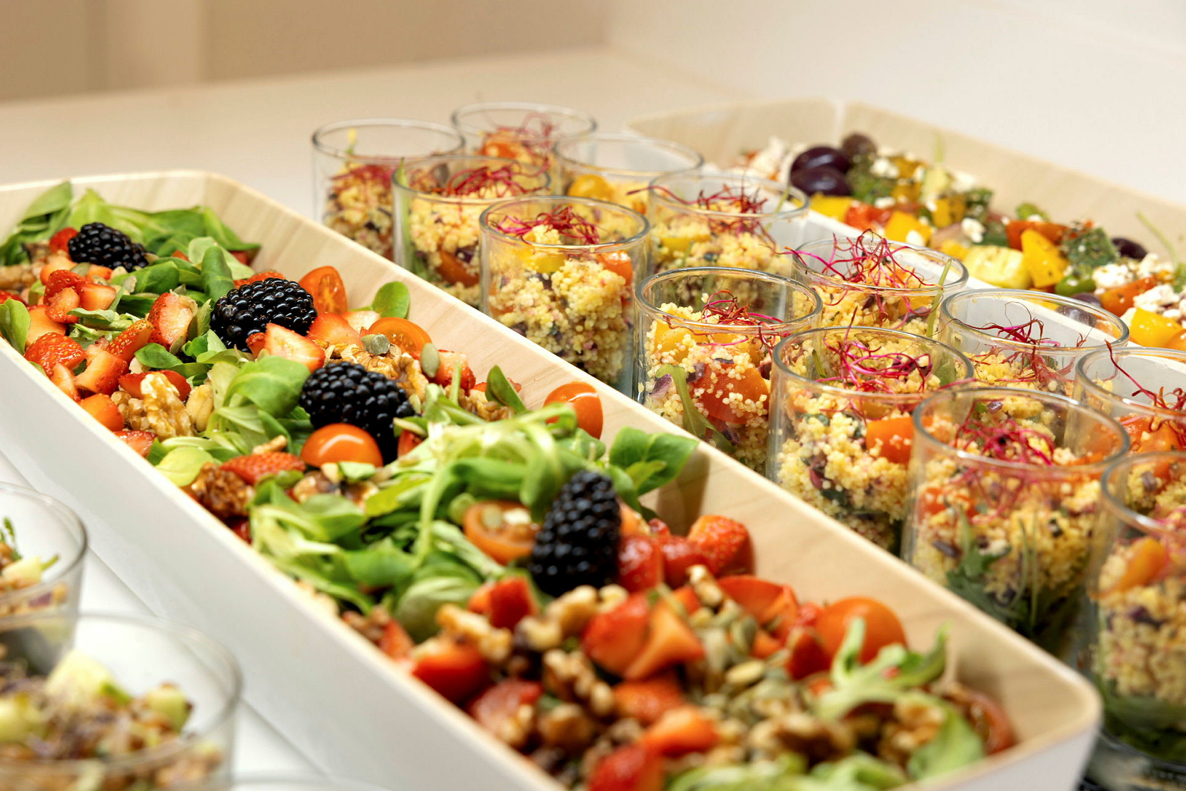 En buffet med salat og quinoa serveret i skåle og glas. (AI-genereret tekst)