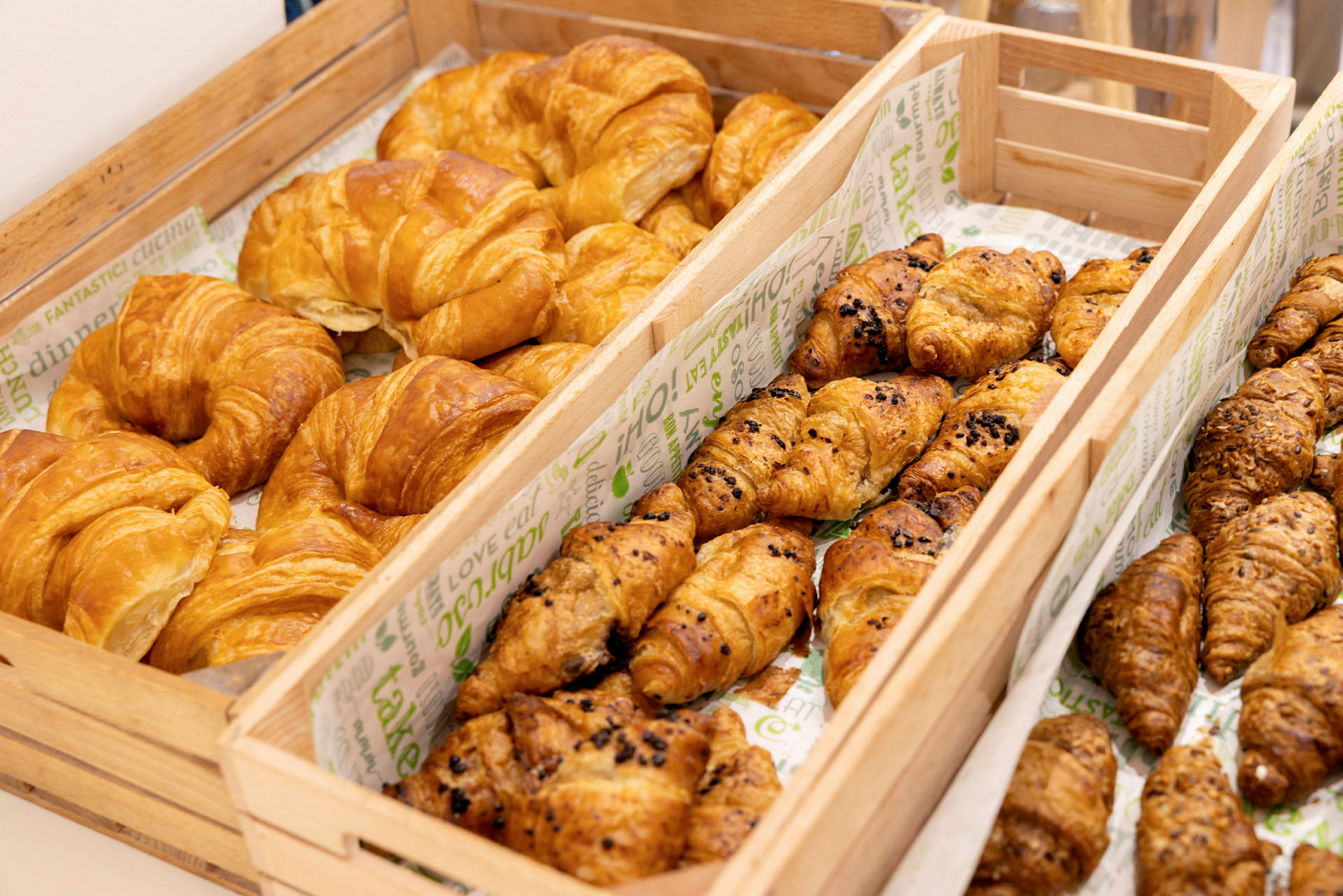 Billede af trækasser fyldt med forskellige typer croissanter. (AI-genereret tekst)