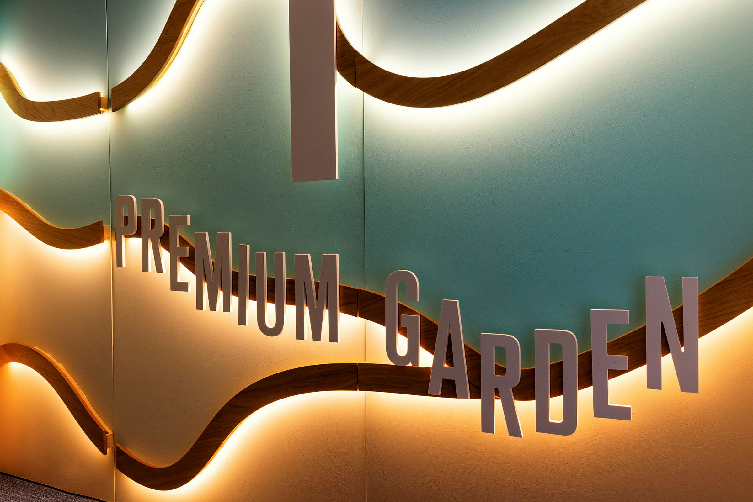 En væg med teksten 'Premium Garden' og bølgeformede detaljer med belysning. (AI-genereret tekst)