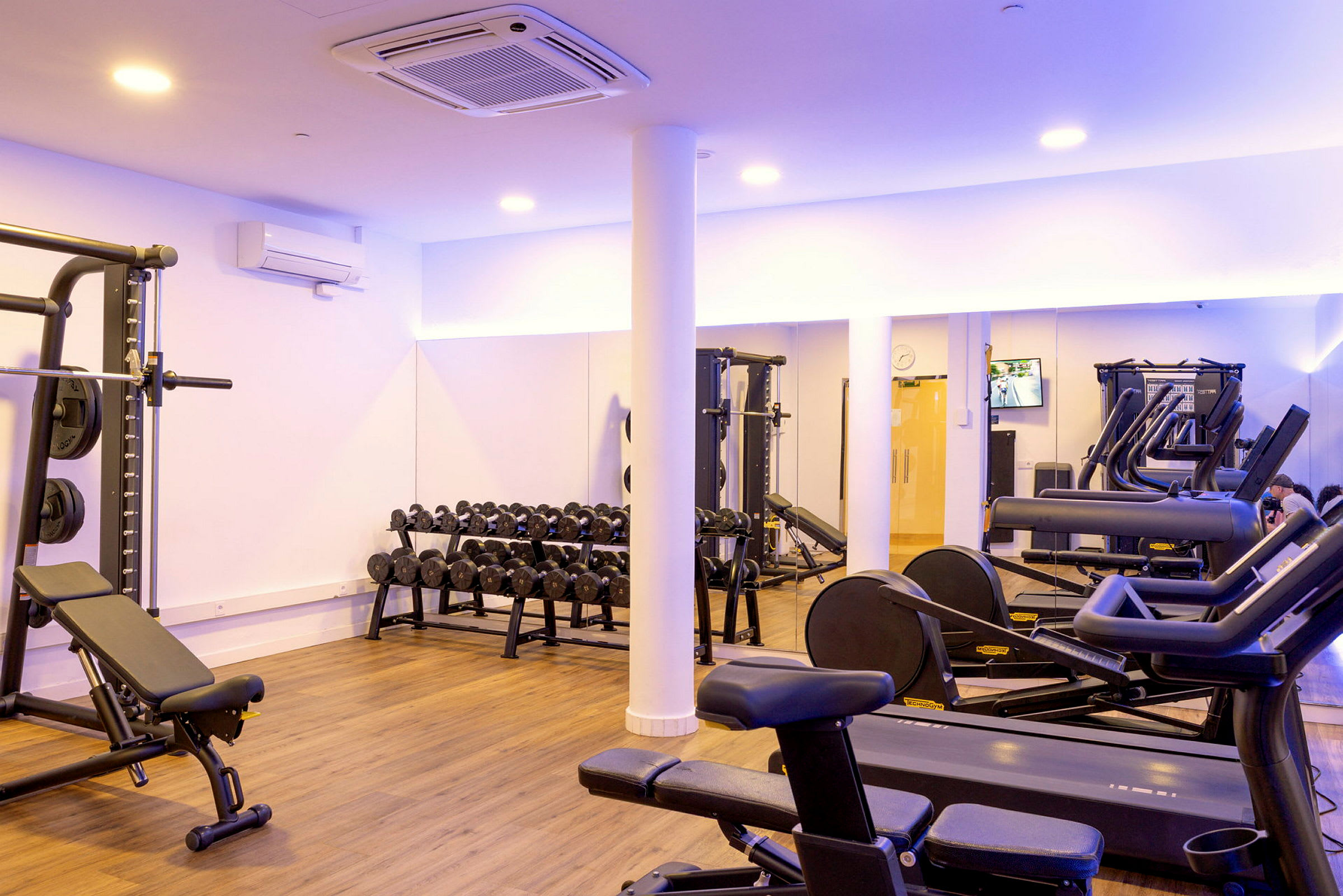 Et fitnesscenter med træningsudstyr såsom løbebånd, bænkpres og håndvægte. (AI-genereret tekst)