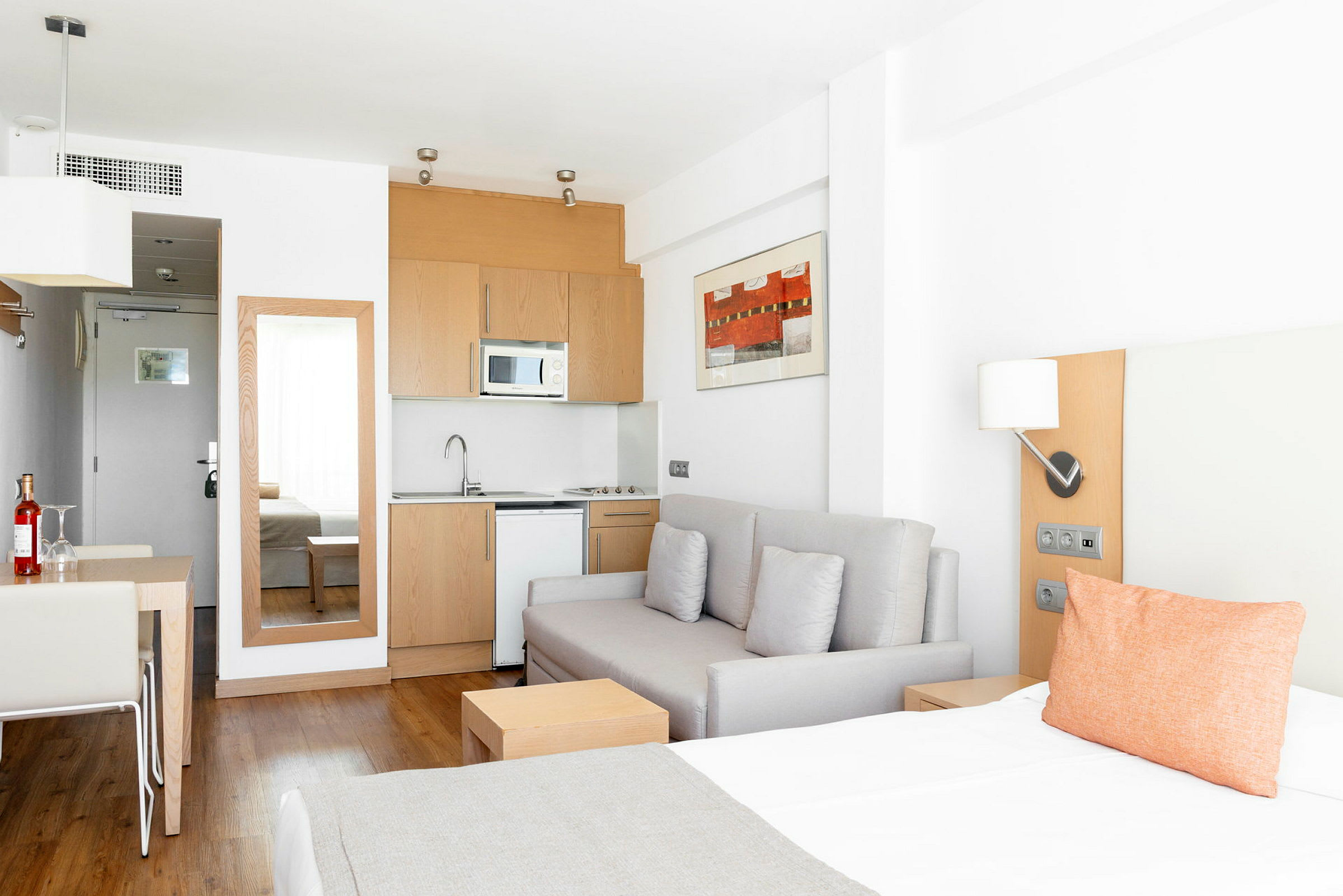 Et lyst hotelværelse med en sovesofa, et tekøkken og et spisebord. (AI-genereret tekst)