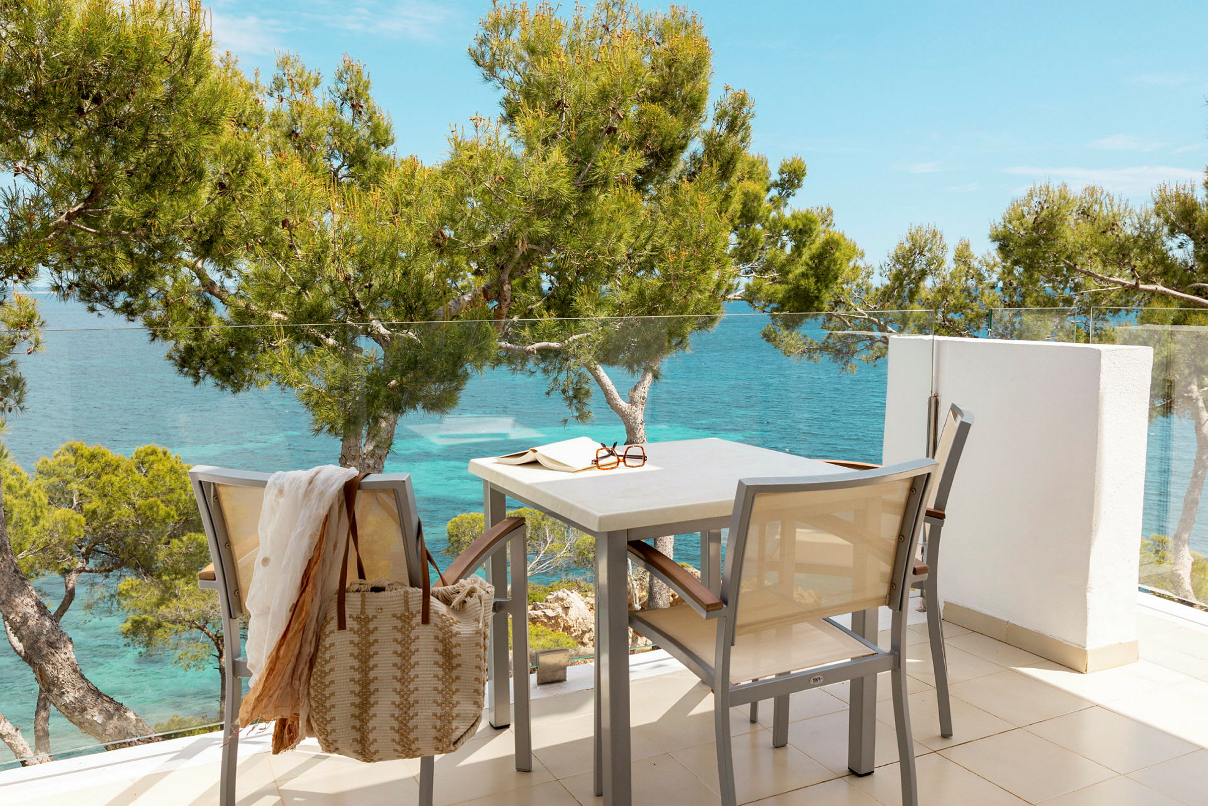 En terrasse med møbler, udsigt over havet og omkringliggende træer. (AI-genereret tekst)