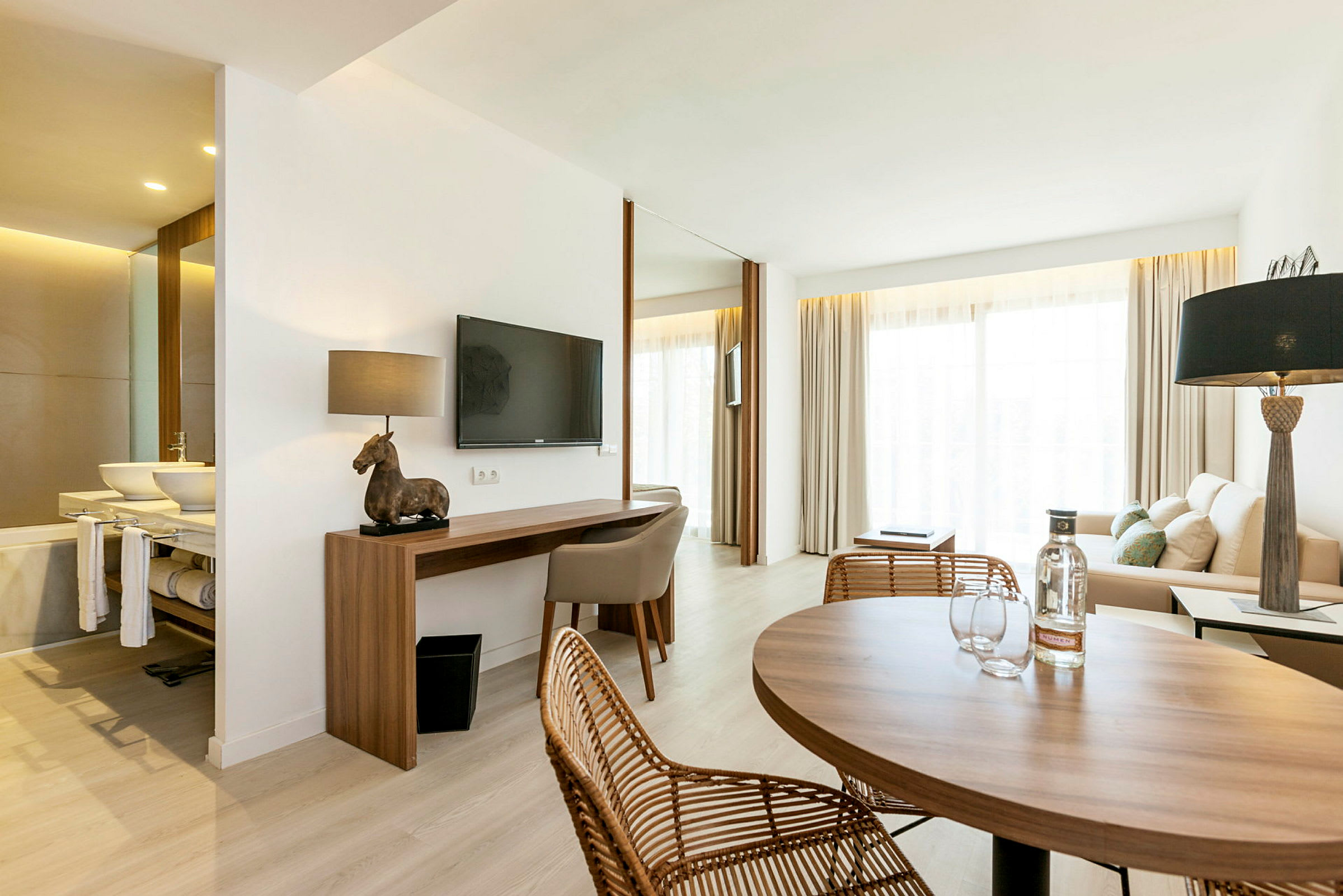 Et moderne hotelværelse med siddeområde, skrivebord og bord. (AI-genereret tekst)