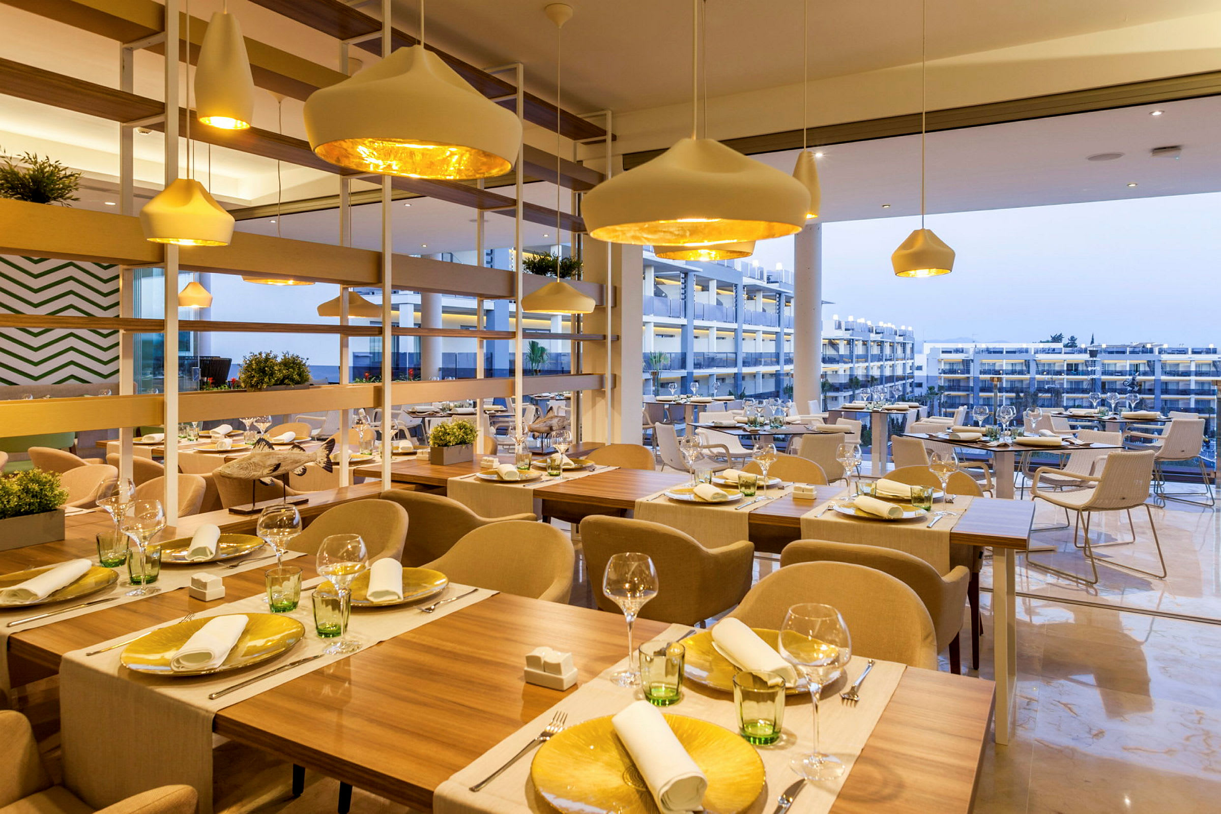 Billede af en moderne restaurant med dækkede borde og store vinduer, der viser udsigten udenfor. (AI-genereret tekst)