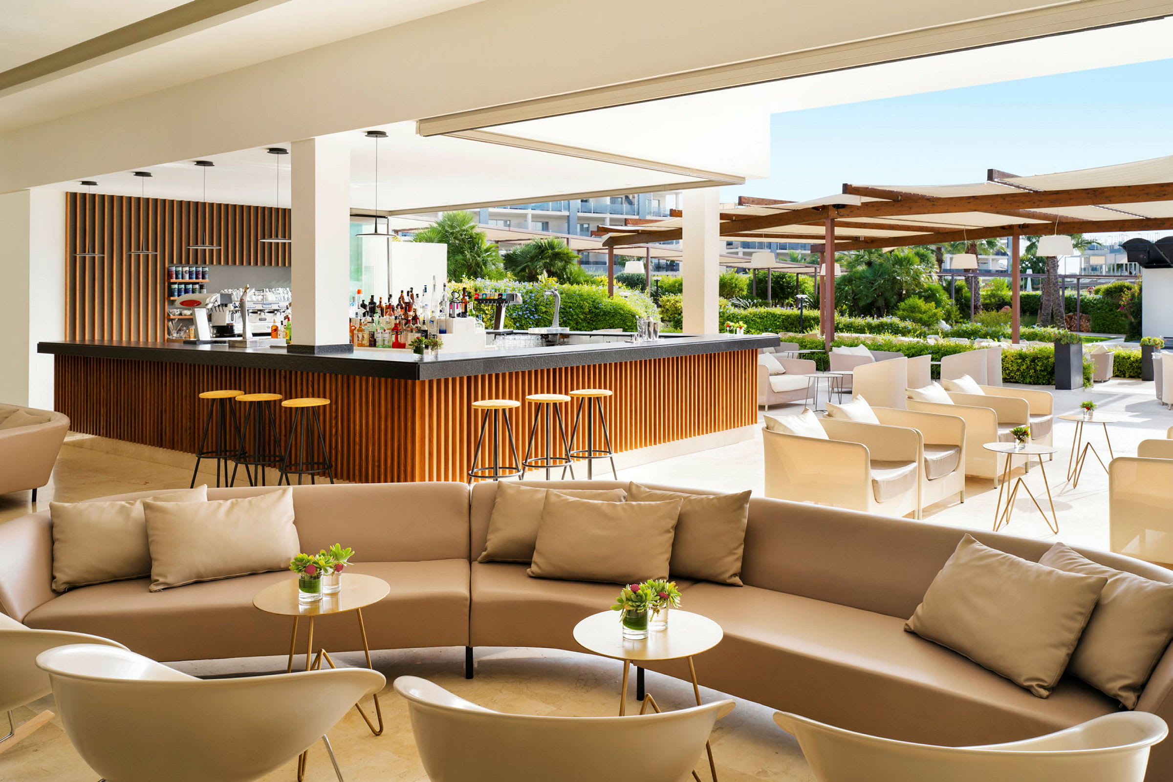 Moderne udendørs bar med komfortable siddegrupper og grønne omgivelser i baggrunden. (AI-genereret tekst)