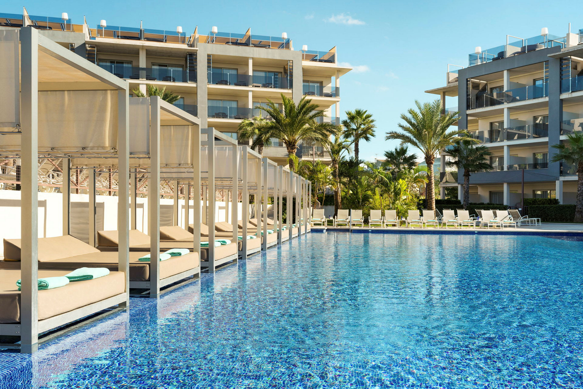 Udendørsområde med pool, liggestole og hotelbygninger. (AI-genereret tekst)