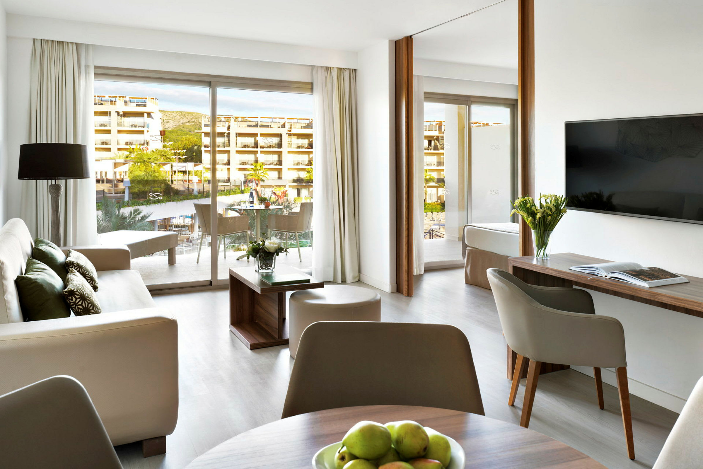 Moderne indrettet hotelsuite med siddeområde, bord og altan. (AI-genereret tekst)