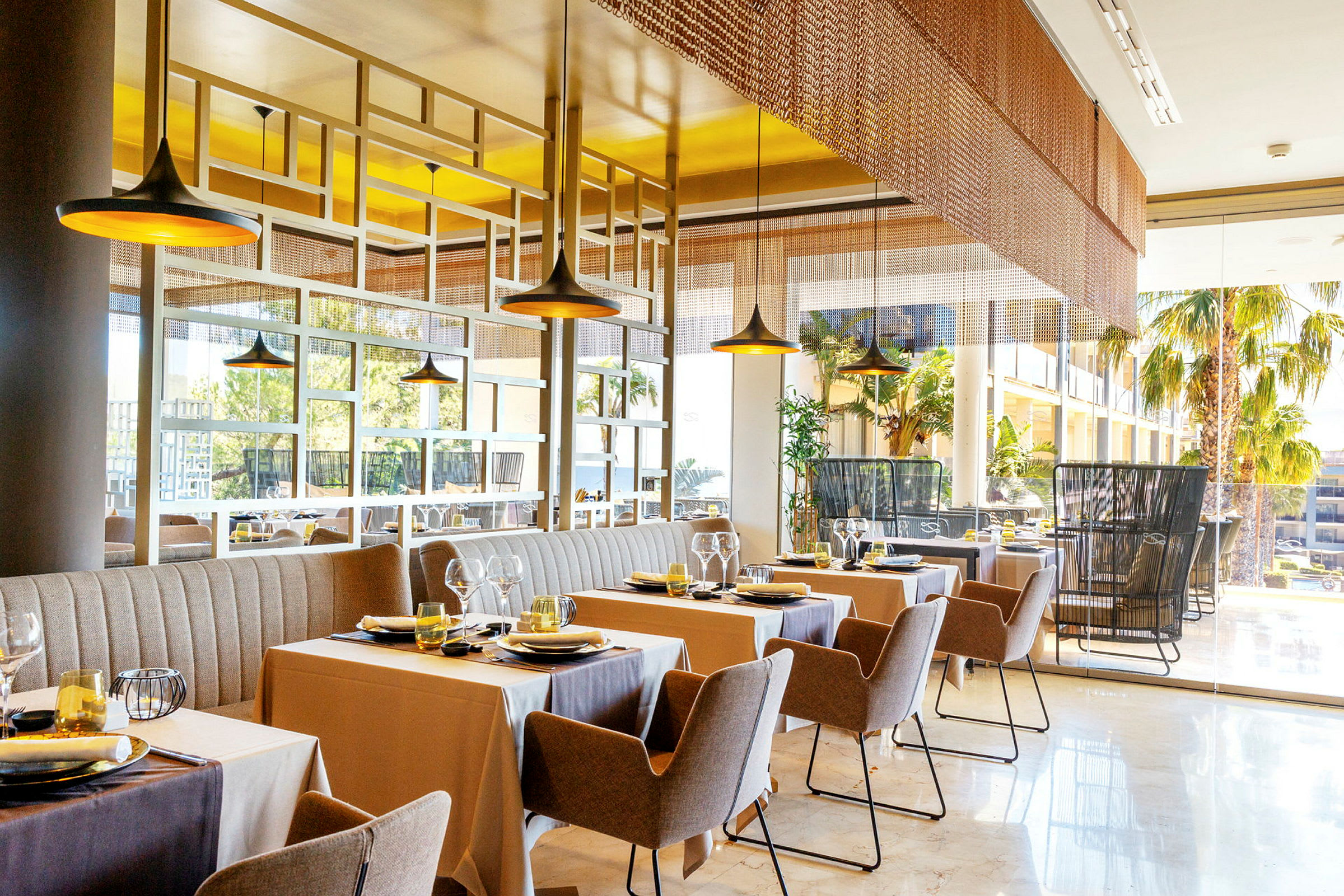 Billede af en moderne restaurant med opdækkede borde og stole, store vinduer samt indretning i behagelige farver. (AI-genereret tekst)