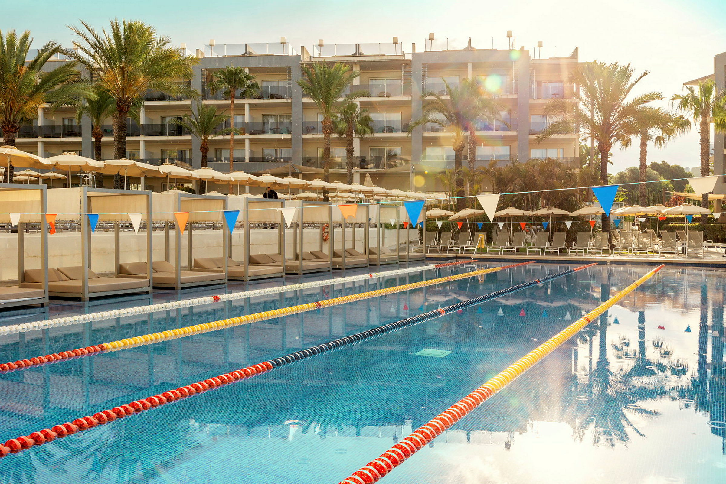 En swimmingpool ved et hotel med liggestole og parasoller i baggrunden. (AI-genereret tekst)