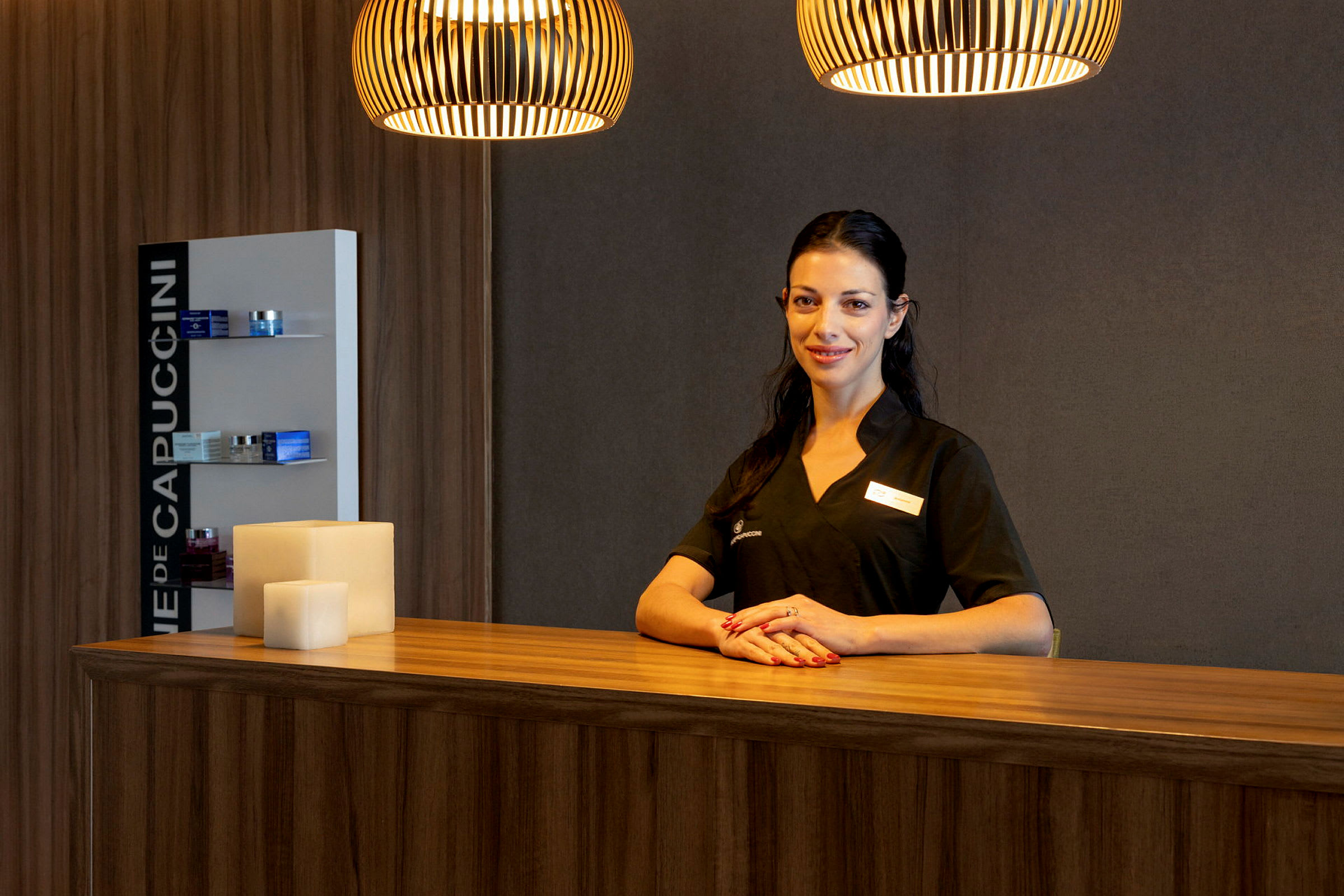 En kvinde i arbejdstøj står bag en receptionsskranke i en varm belysning. (AI-genereret tekst)