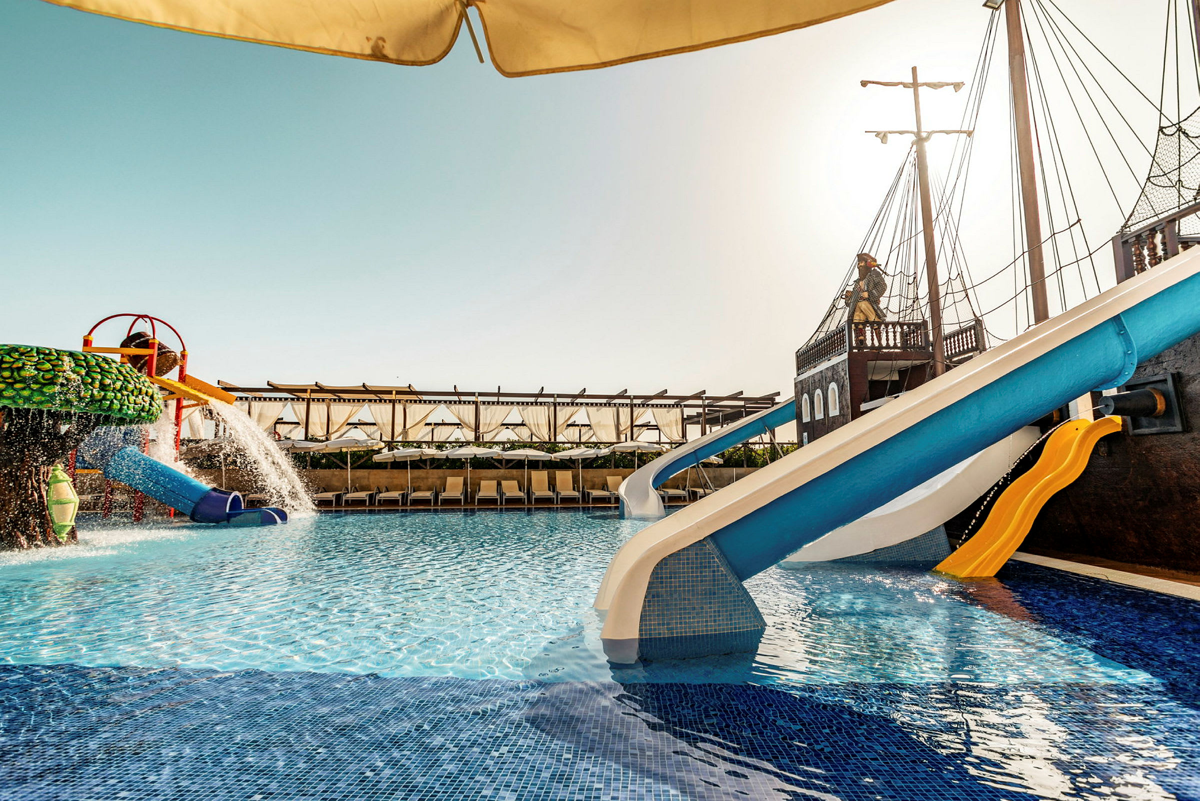 En swimmingpool med vandrutsjebaner og en temadekoration, der ligner et piratskib. (AI-genereret tekst)