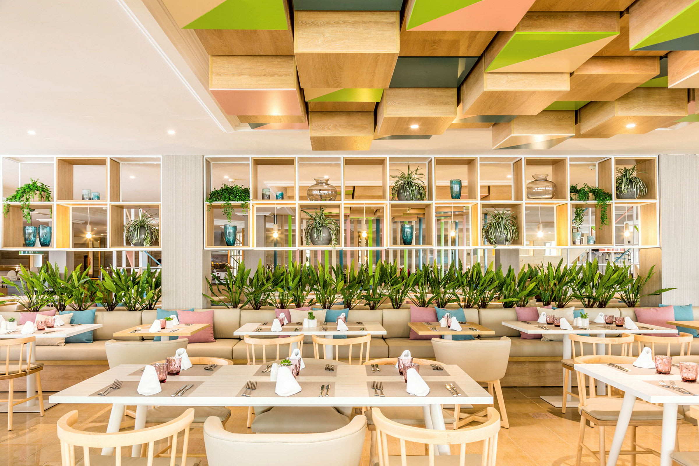 Moderne restaurant med træborde, stole og dekorationer, herunder planter og puder. (AI-genereret tekst)