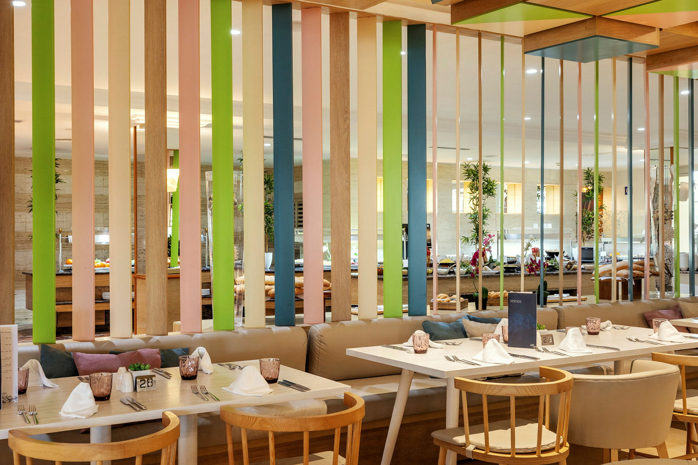Interiør af en restaurant med borde, stole og en farverig skærmvæg. (AI-genereret tekst)