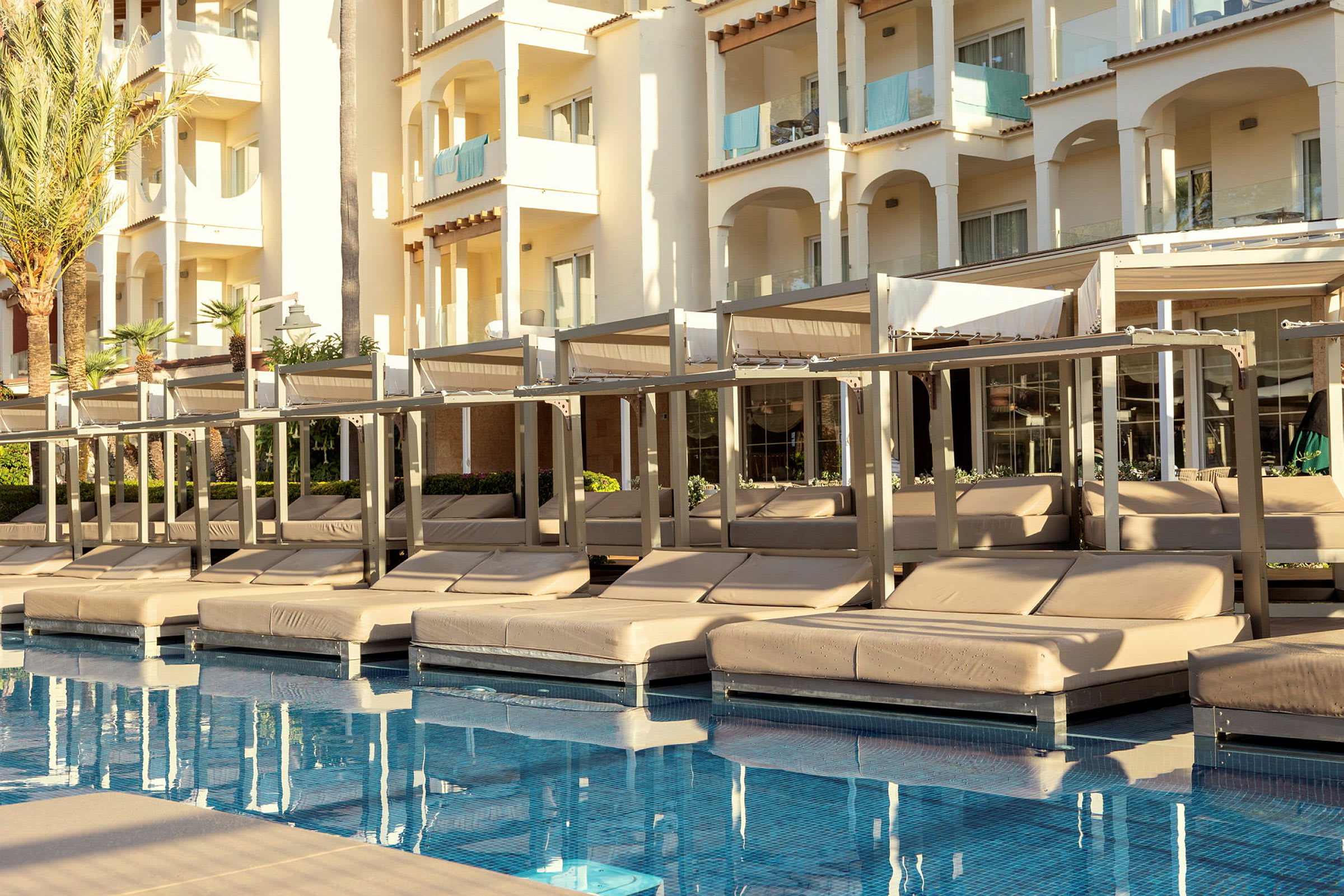 Solsenge ved en pool med en hotelbygning i baggrunden. (AI-genereret tekst)
