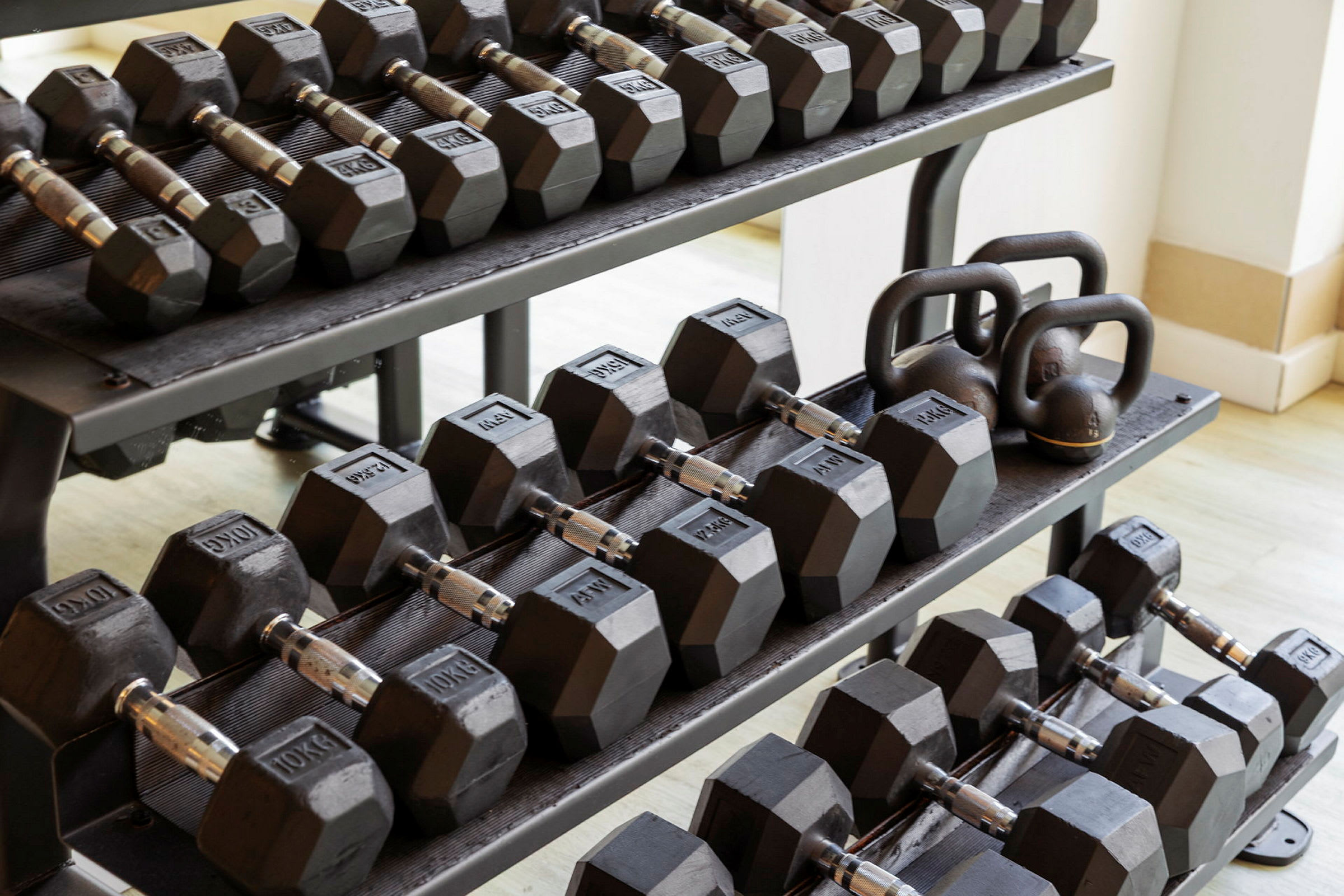 Et stativ med vægthåndvægte og kettlebells i sort metal. (AI-genereret tekst)