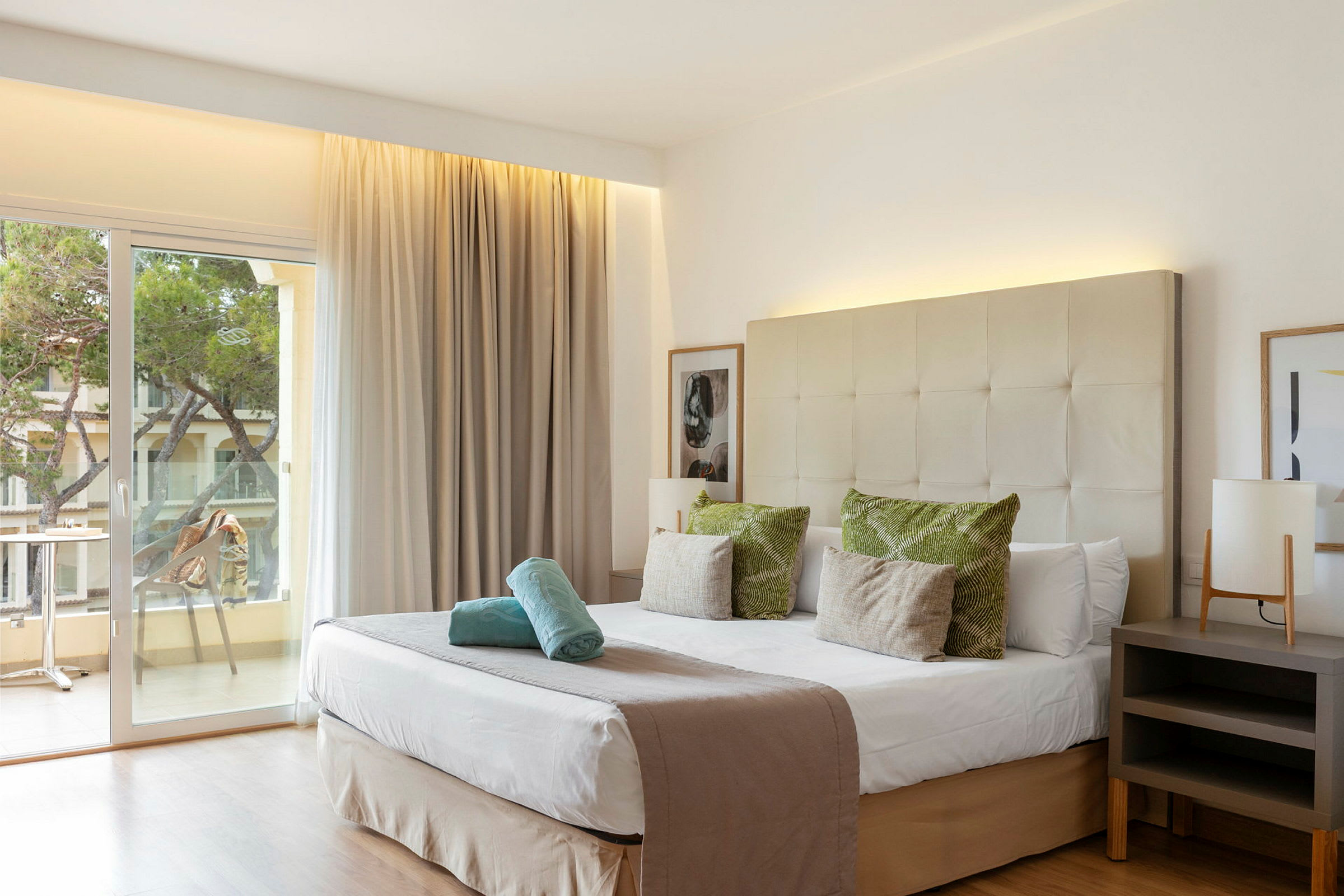 Hotelværelse med dobbeltseng, indretning i neutrale farver og en balkon med udsigt. (AI-genereret tekst)