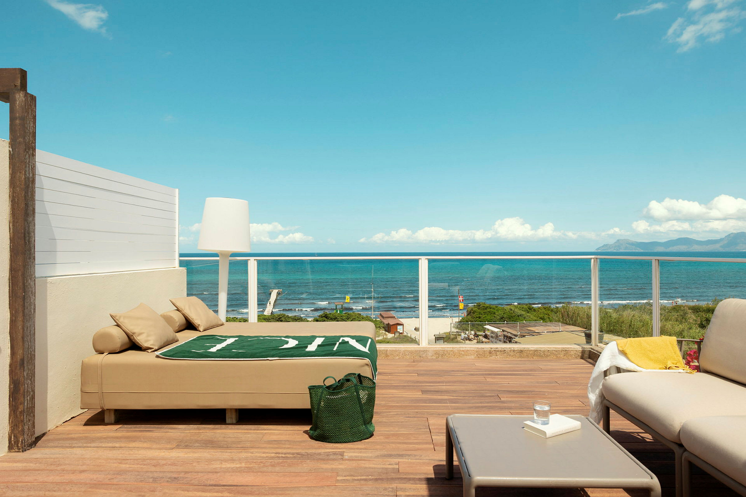 Terrasse med moderne møblering og udsigt over havet, inklusive en solseng, sofamøbler og bord. (AI-genereret tekst)