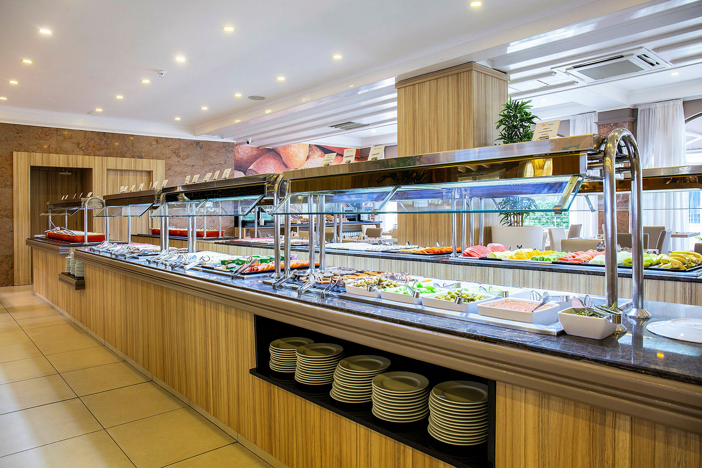 Selvbetjeningsbuffet med forskellige retter i en lys spiseområde. (AI-genereret tekst)