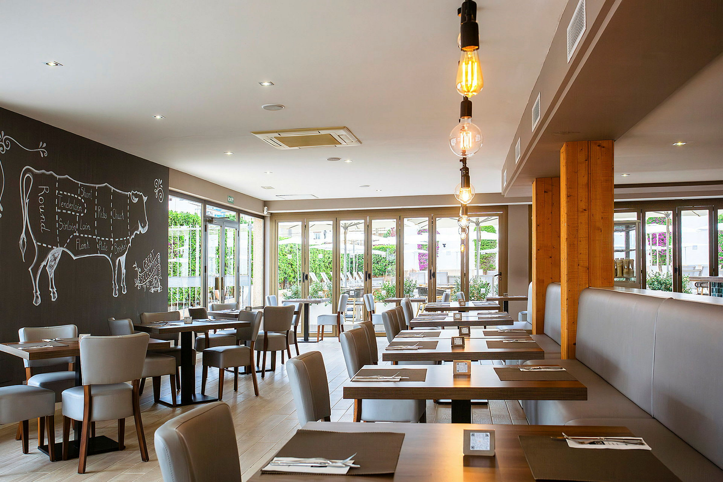 En moderne restaurant med borde og stole, dekoreret med et vægmaleri af en ko. (AI-genereret tekst)