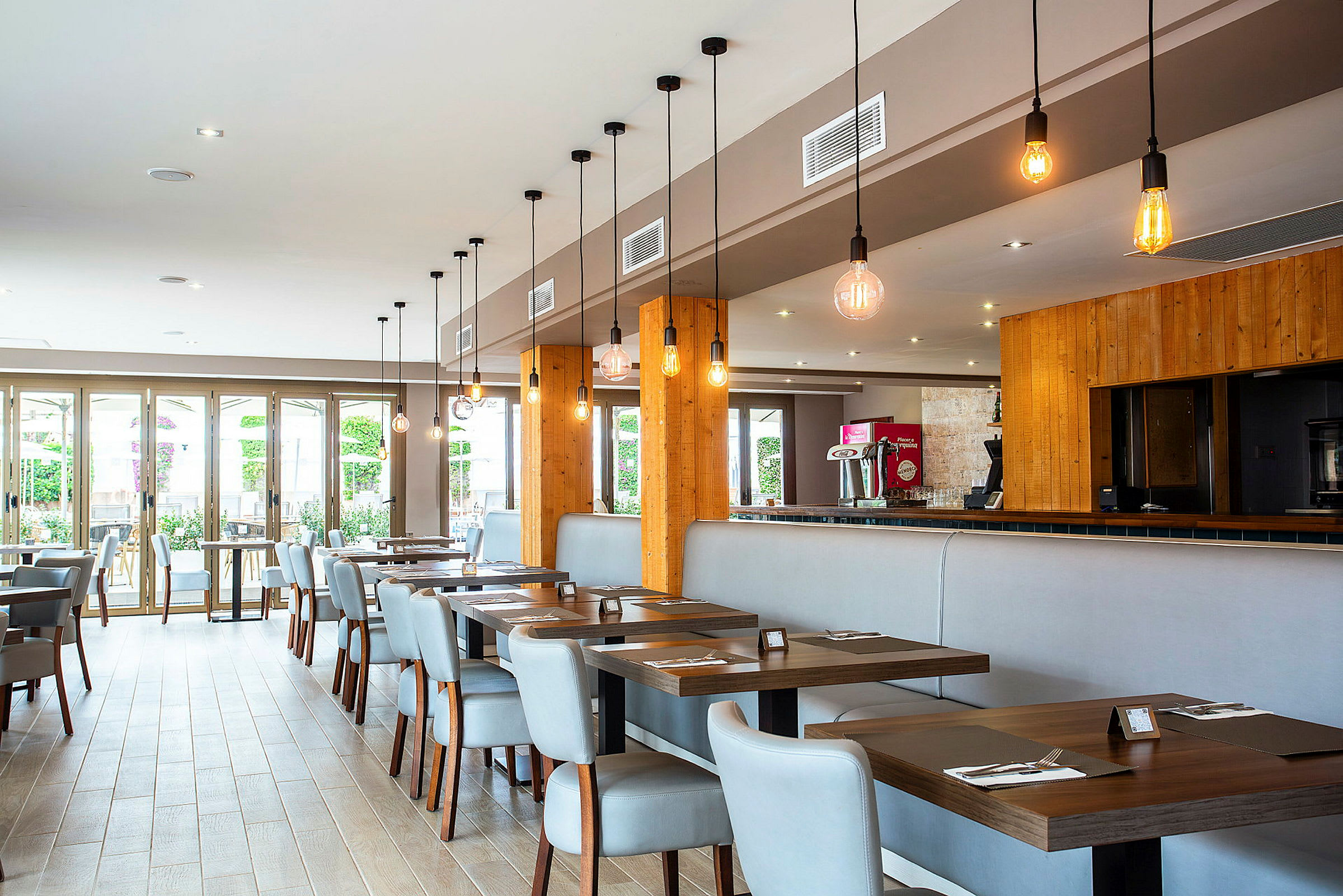 Moderne restaurantborde med stole i lys indretning og hængende lamper. (AI-genereret tekst)