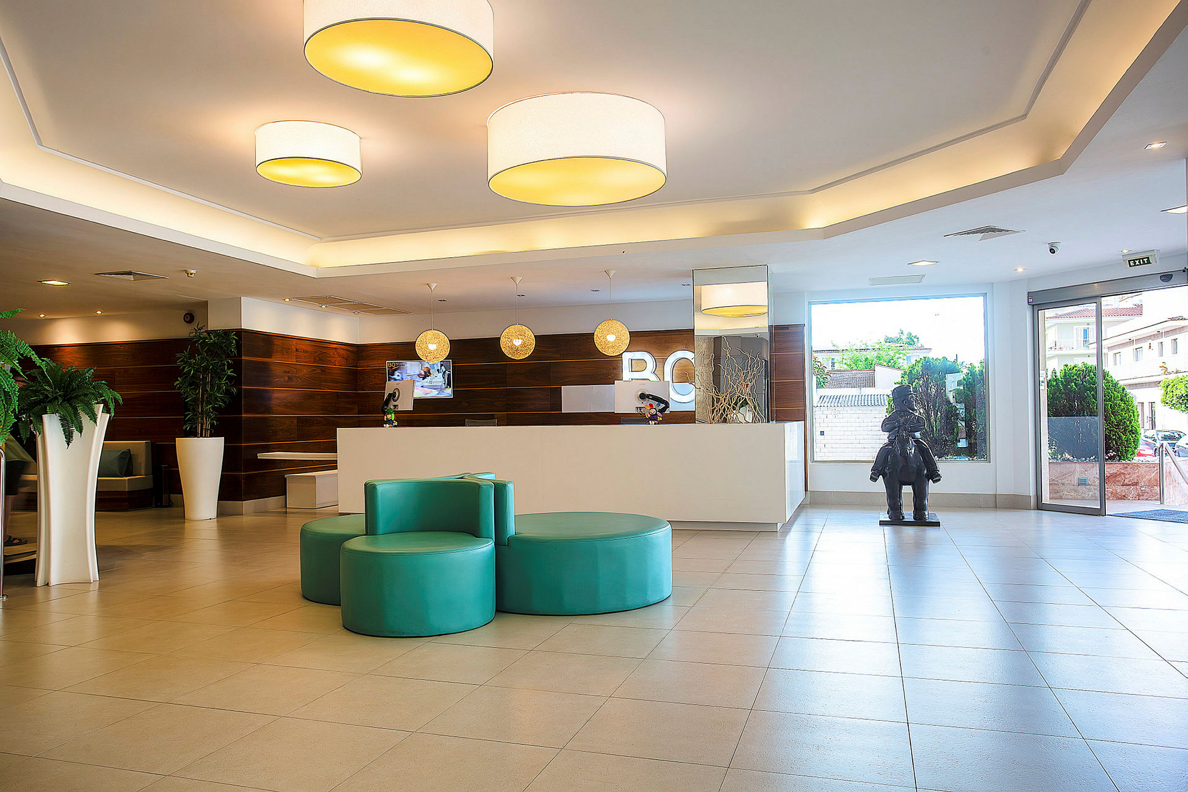 Hotellobby med reception, siddearrangement og en vinduesdør. (AI-genereret tekst)