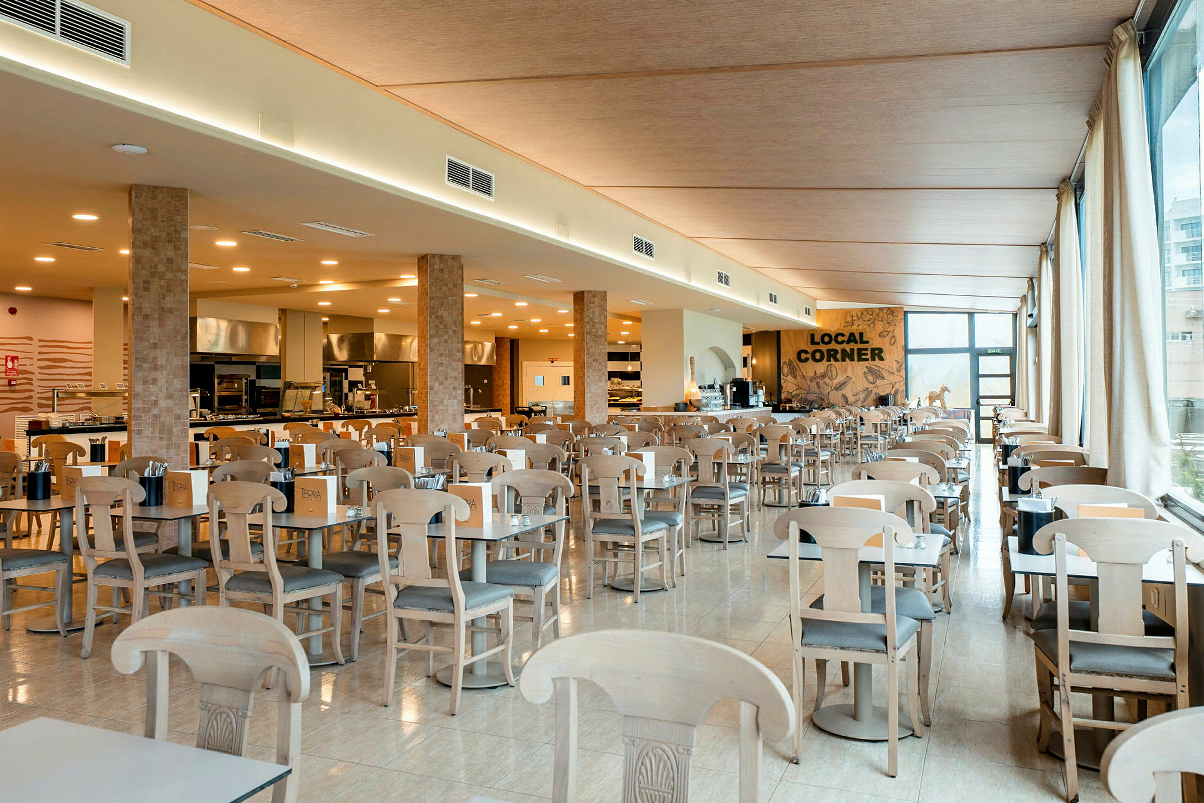 Interiør af en rummelig restaurant med mange borde og stole samt en serveringsdisk i baggrunden. (AI-genereret tekst)