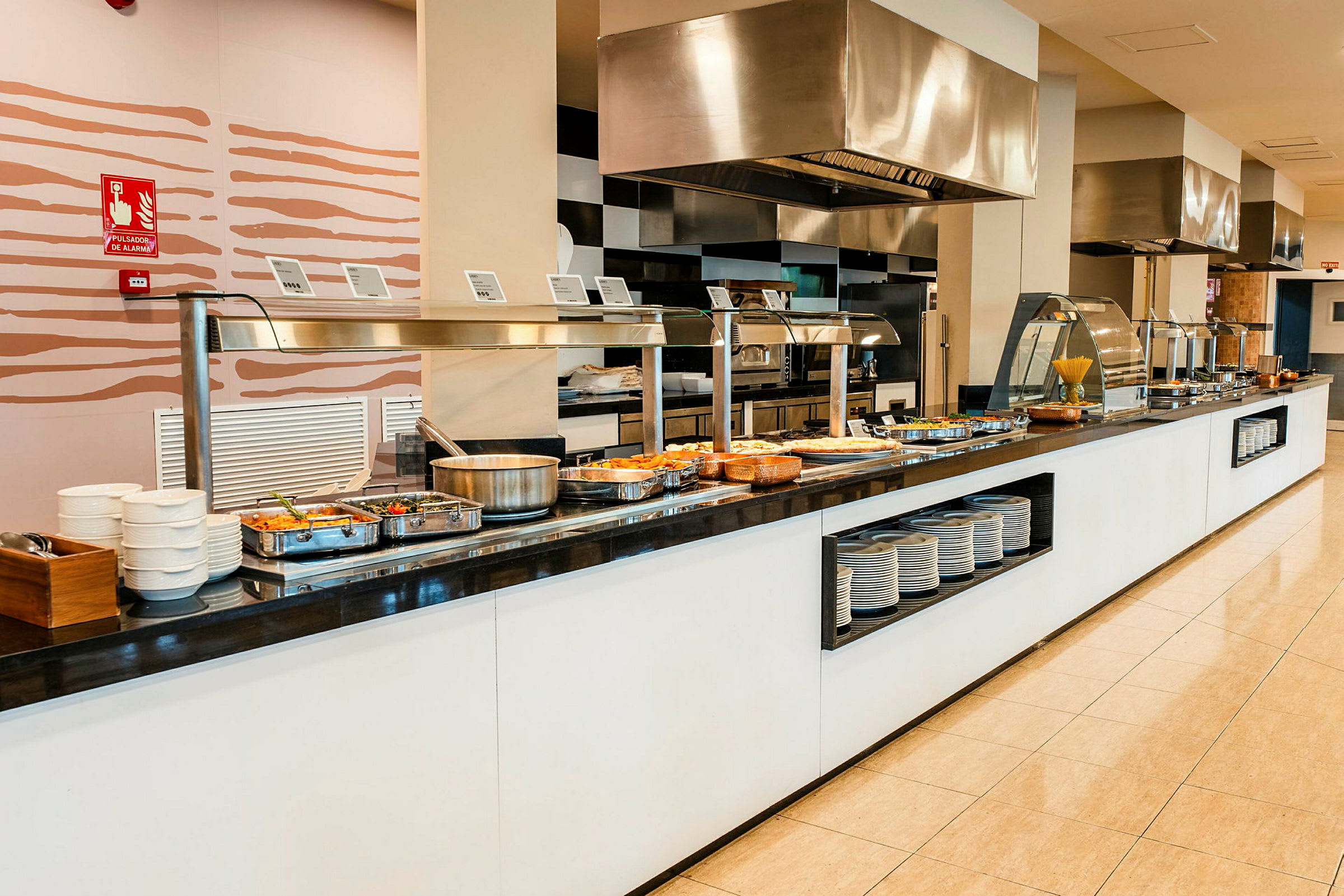 Buffet med forskellige retter, tallerkener og bestik ved siden. (AI-genereret tekst)