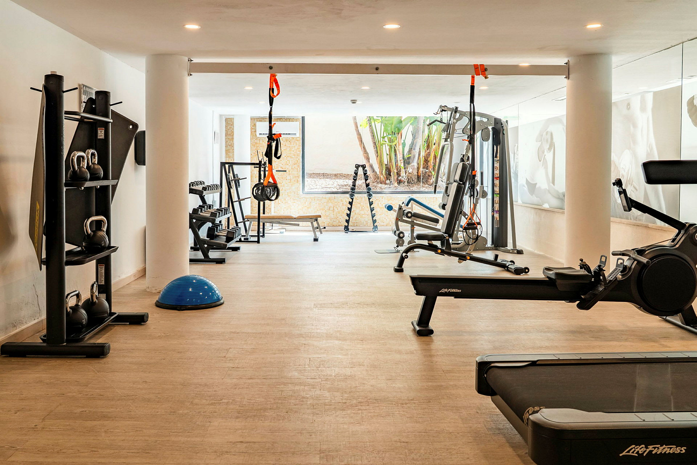 Billede af et fitnessrum med forskellige træningsmaskiner som løbebånd, romaskine og fitnessudstyr. (AI-genereret tekst)