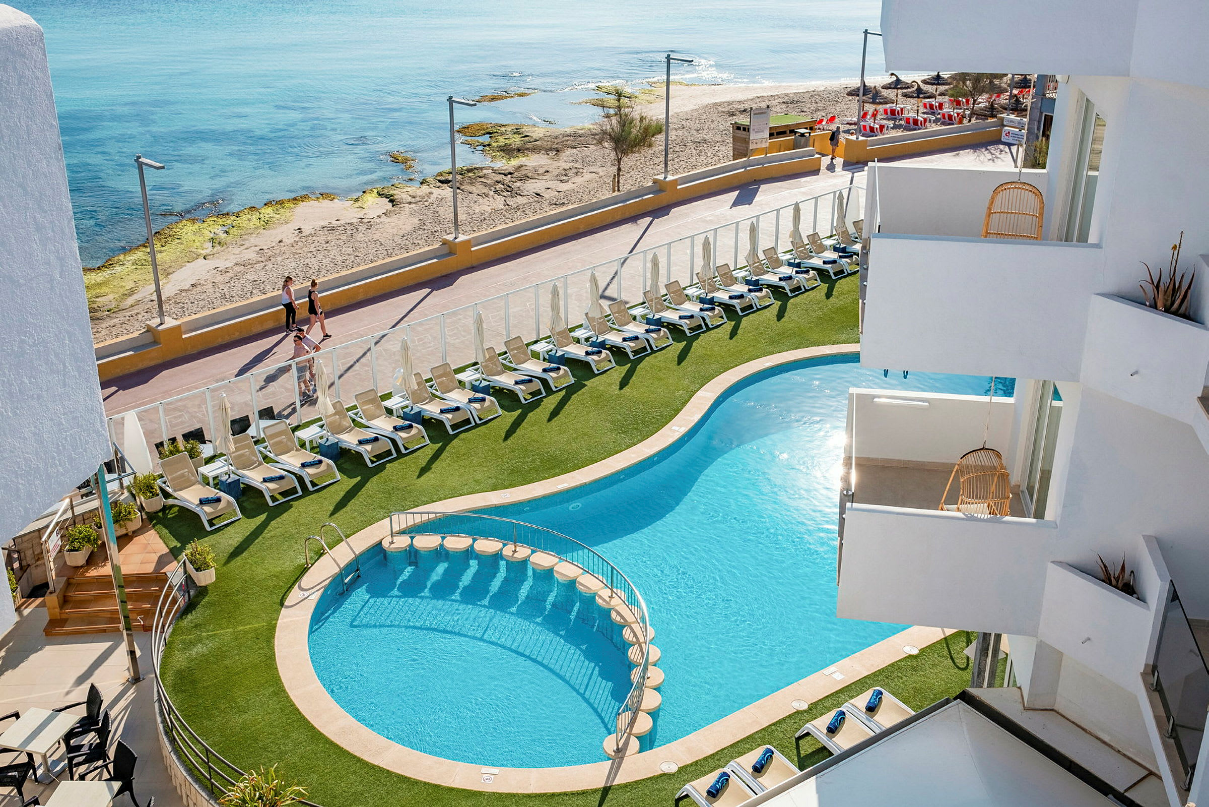 Hotelpool med liggestole og nærhed til strand og gangsti. (AI-genereret tekst)