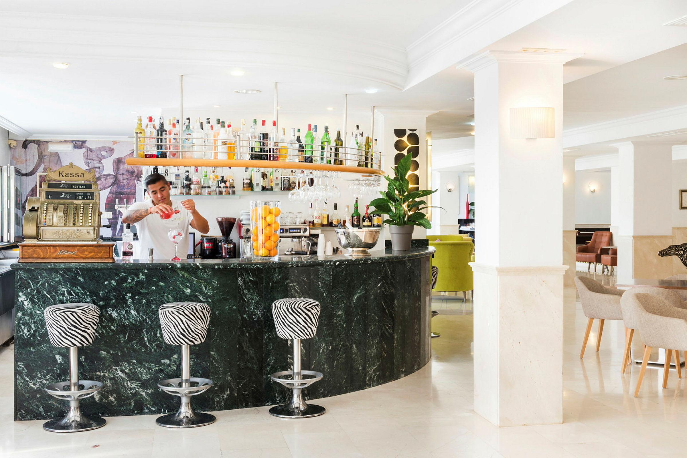 En veloplyst hotelbar med marmordisk og zebramønstrede barstole. (AI-genereret tekst)
