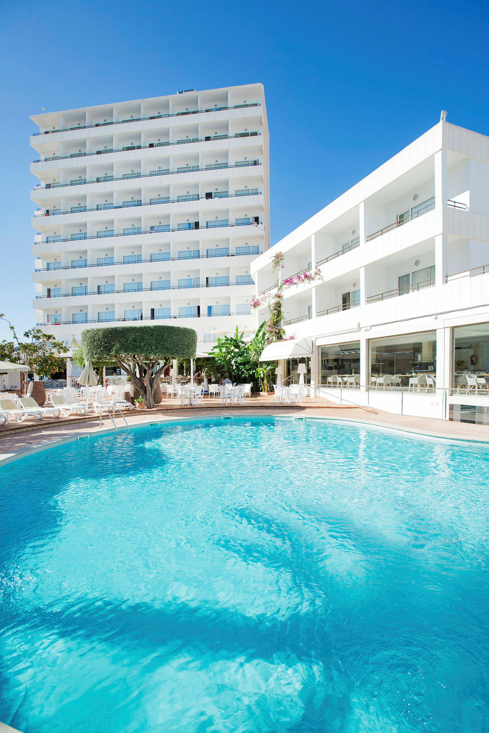 Udendørs pool foran hotelbygning. (AI-genereret tekst)