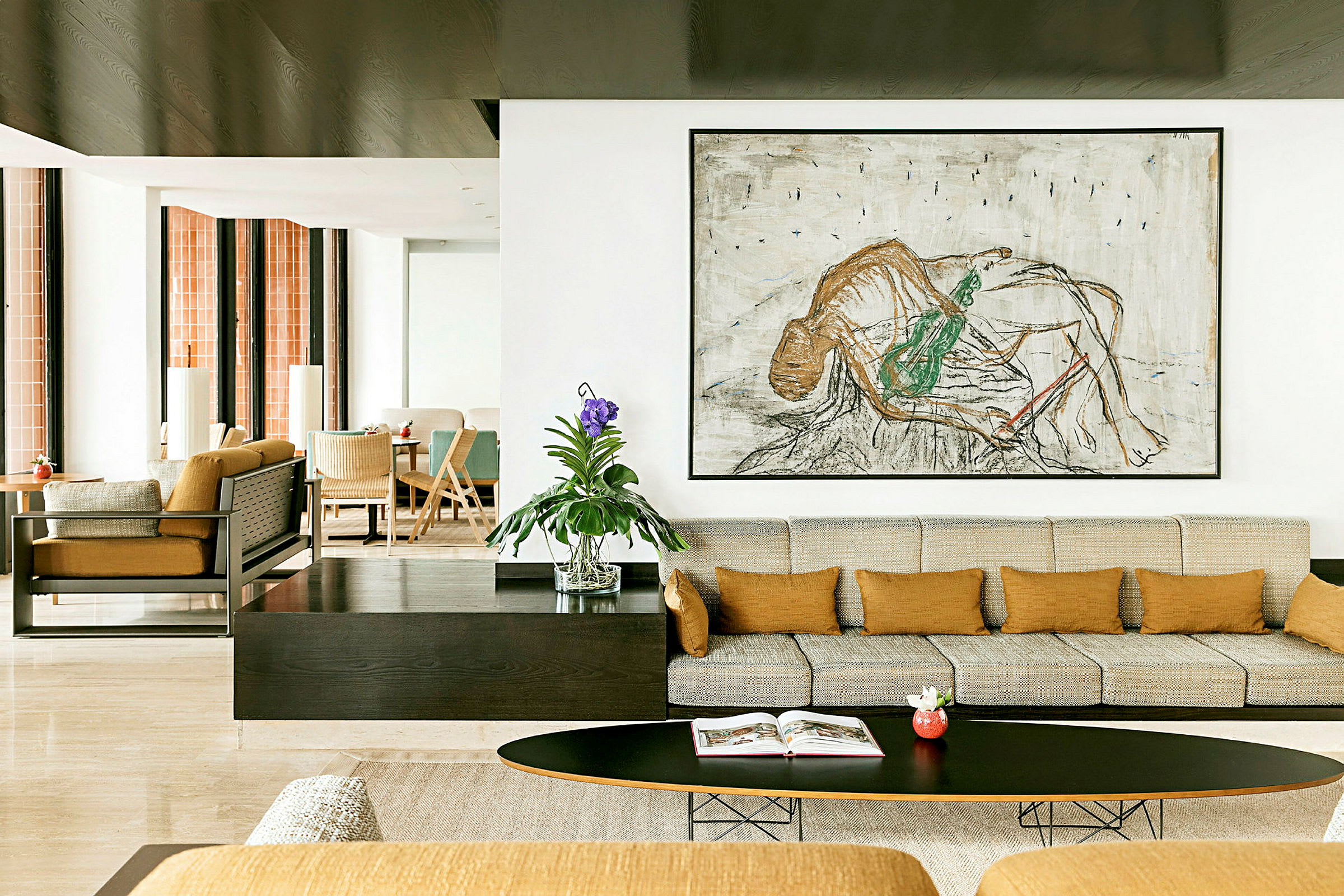 En moderne stue med beige sofa, orange puder og et stort kunstværk på væggen. En grøn plante i en glasvase står på bordet. (AI-genereret tekst)