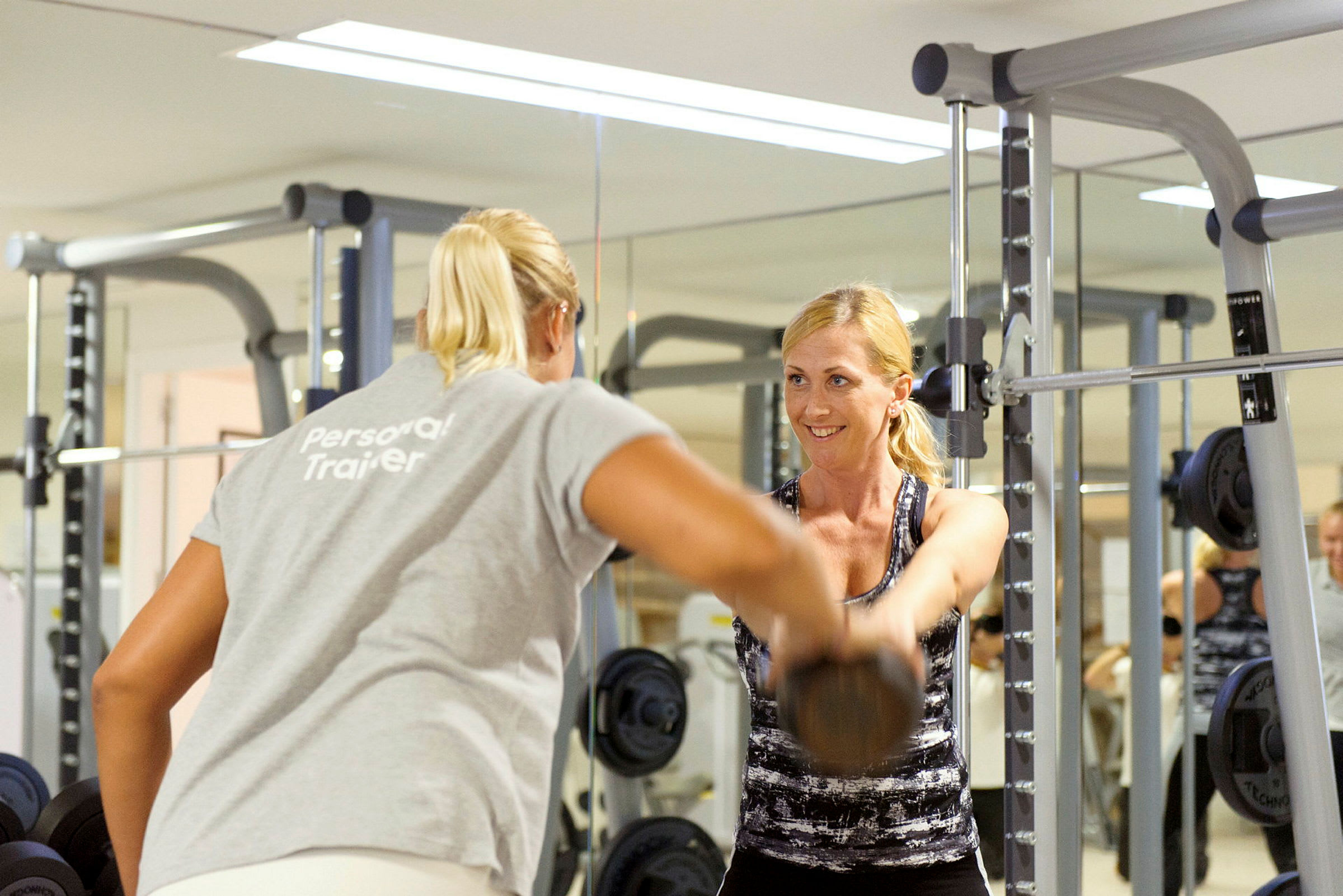 Personlig træner hjælper en kvinde med at træne med håndvægte i et fitnesscenter. (AI-genereret tekst)