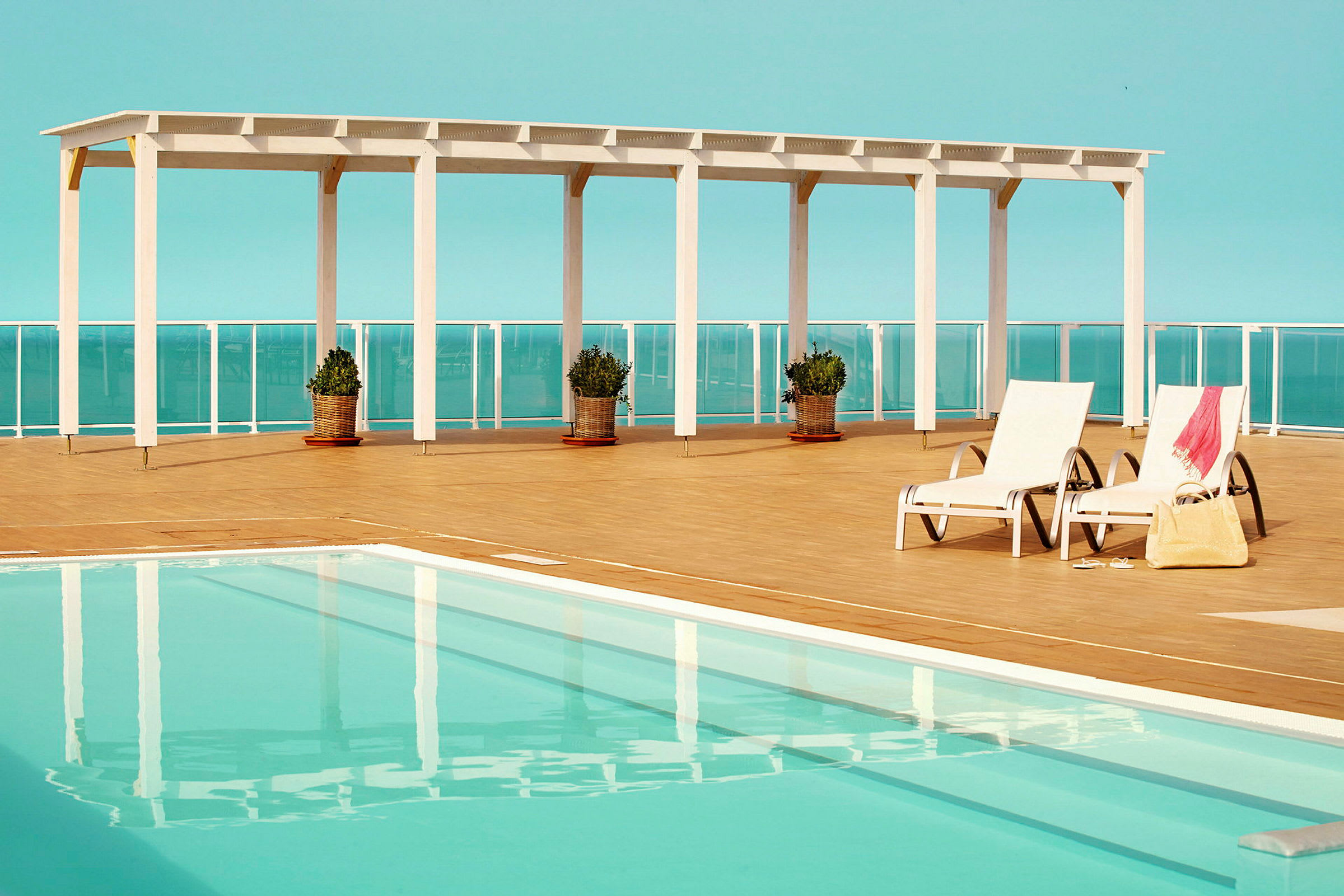 Udendørs pool med liggestole og pergola ved siden af. (AI-genereret tekst)