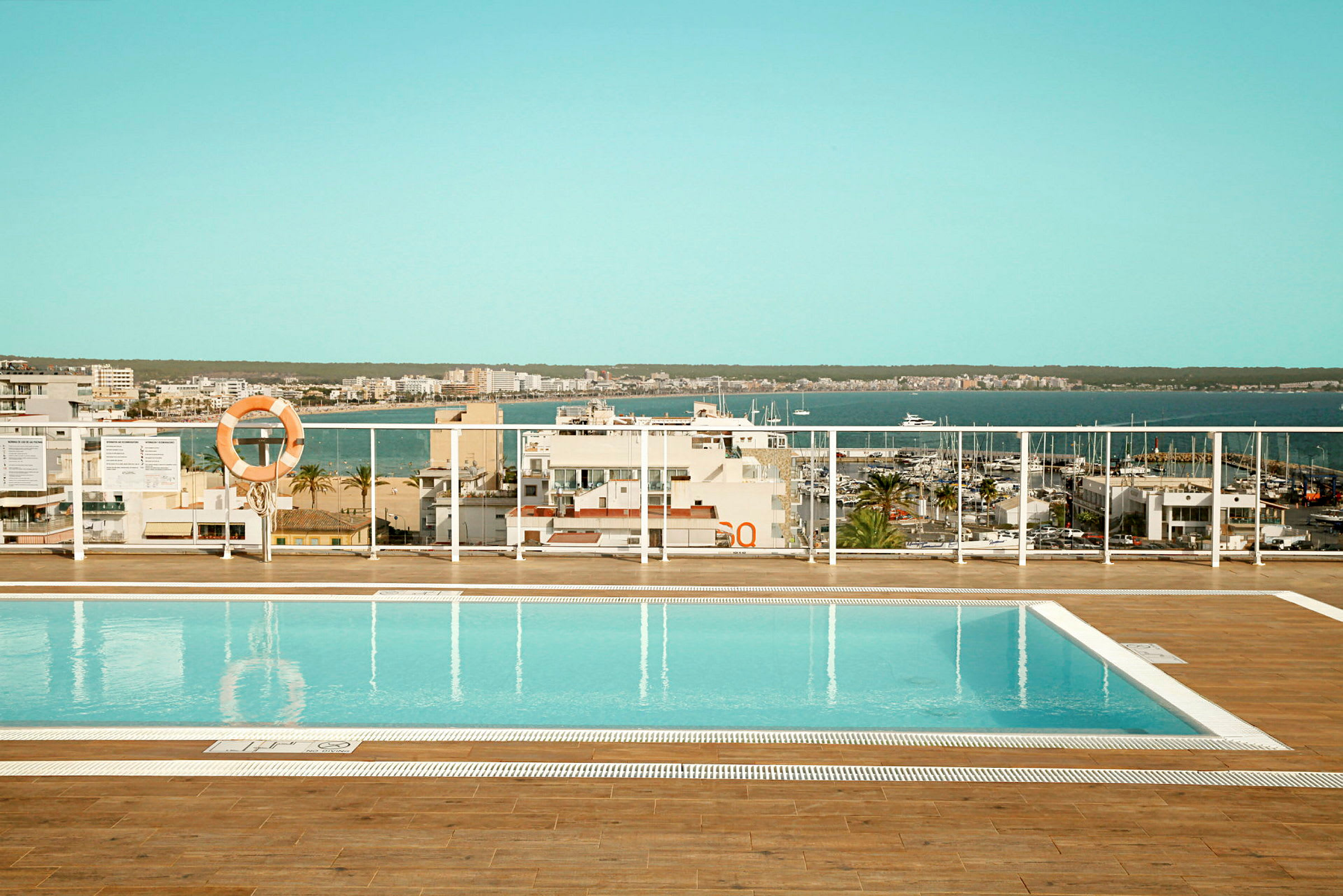 Poolområde med udsigt over marinaer og havet. (AI-genereret tekst)