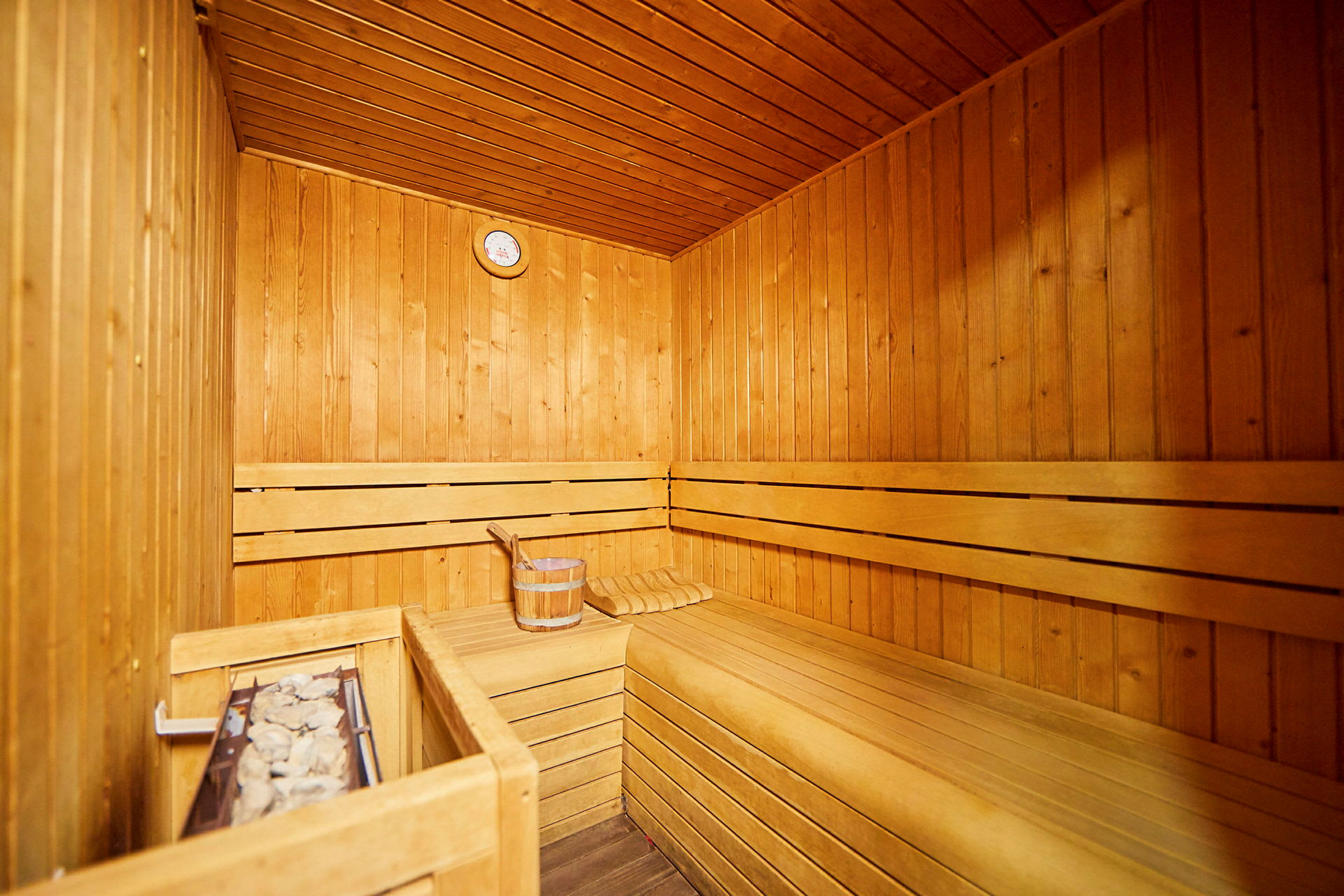 Indersiden af en traditionel træsauna med saunasten og træbænk. (AI-genereret tekst)