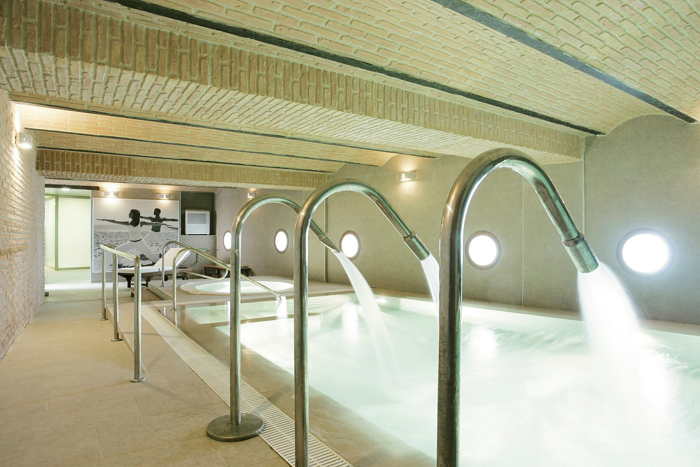 Indendørs pool med strømmende vand fra metalrør. (AI-genereret tekst)