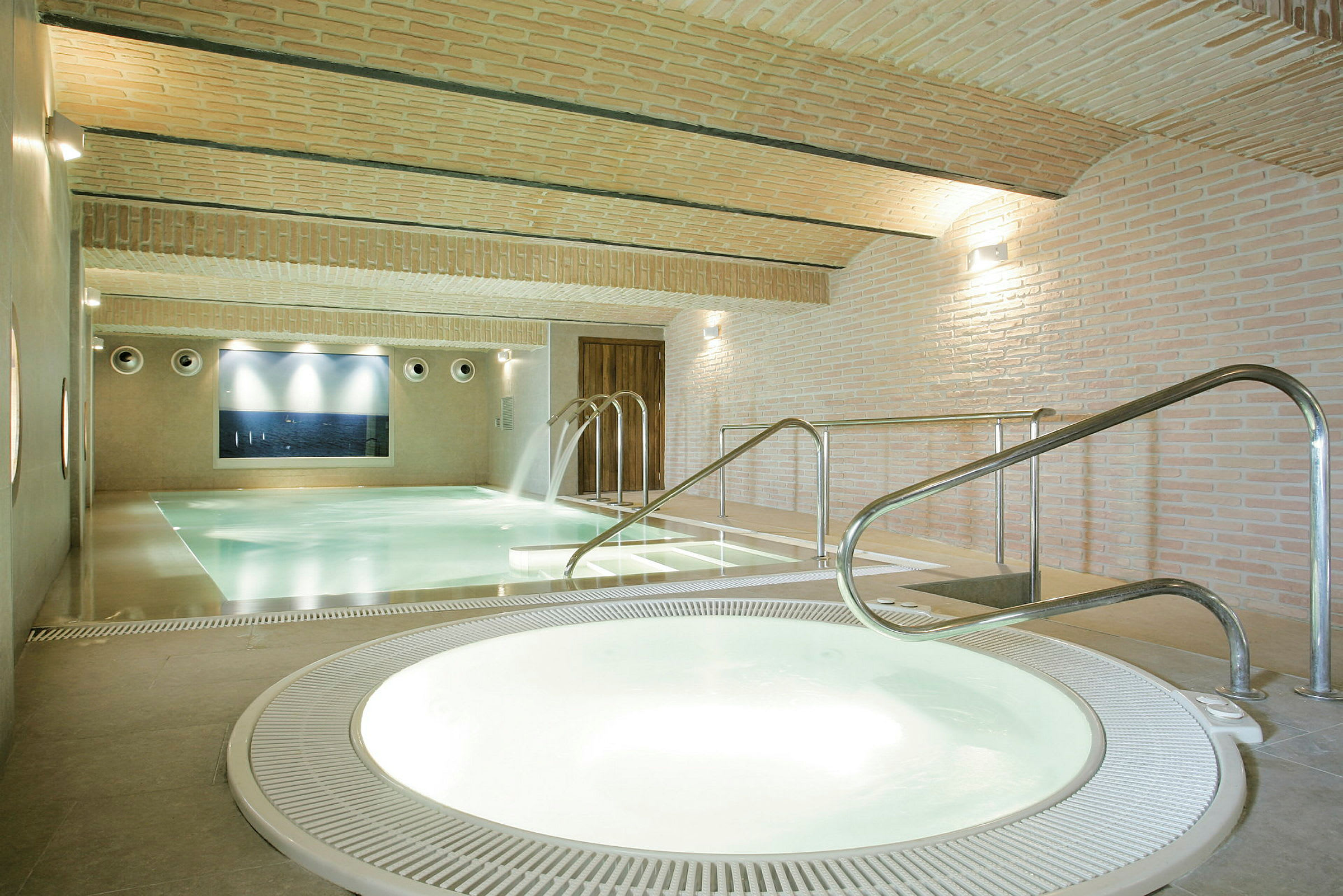 Indendørs poolområde med jacuzzi og pool med vandfald. (AI-genereret tekst)