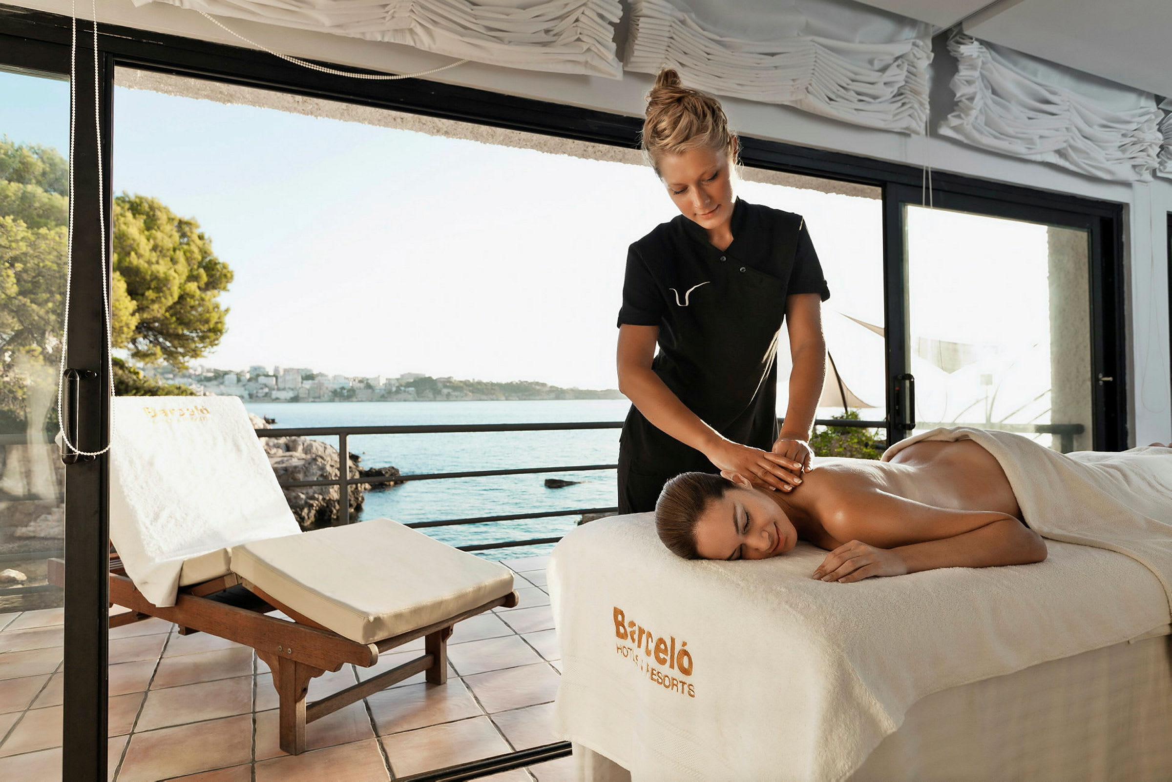 Massage udføres i et lyst miljø med udsigt over havet gennem store glasvinduer. (AI-genereret tekst)