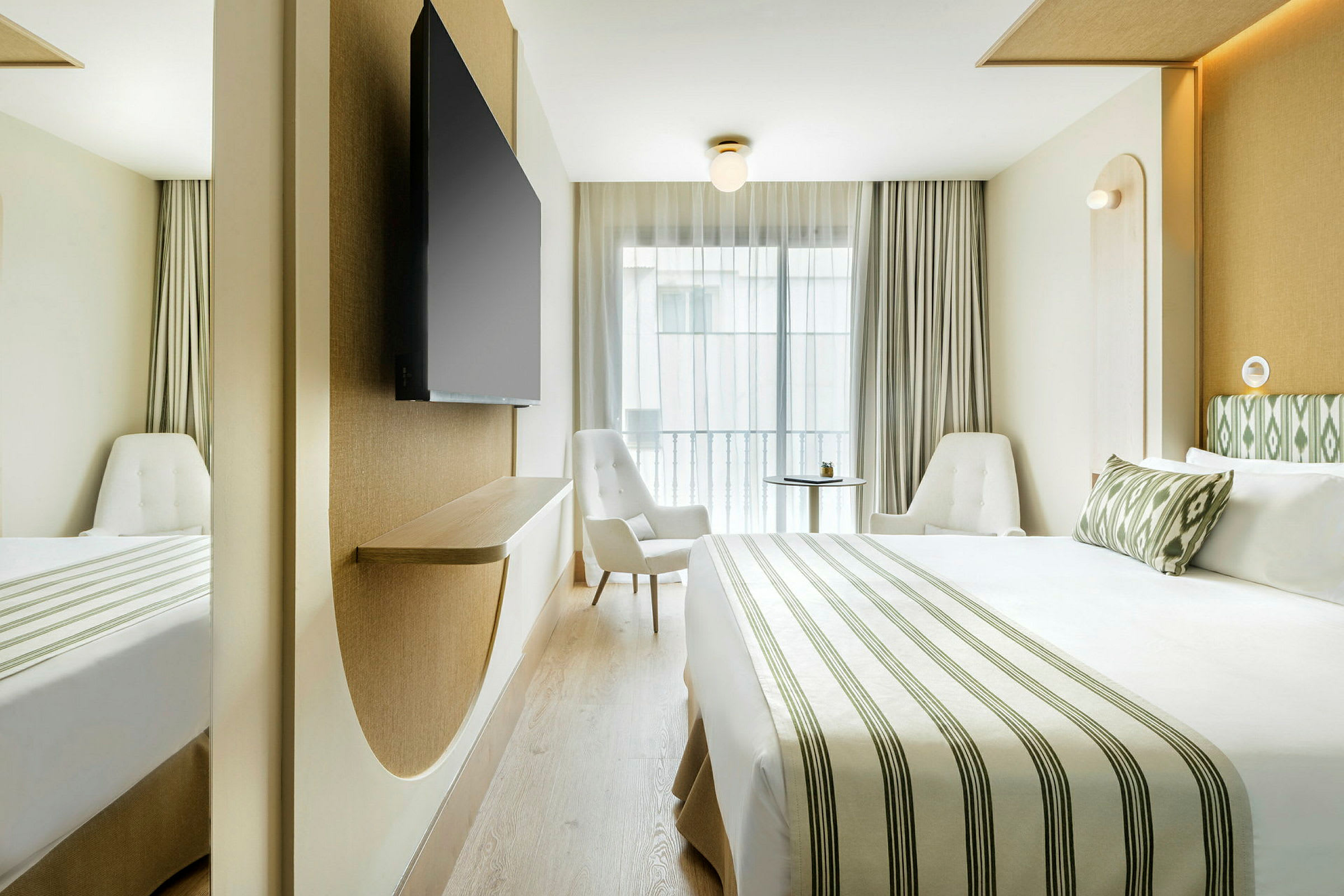 Et moderne hotelværelse med en stor seng, to stole og et vægmonteret TV. (AI-genereret tekst)