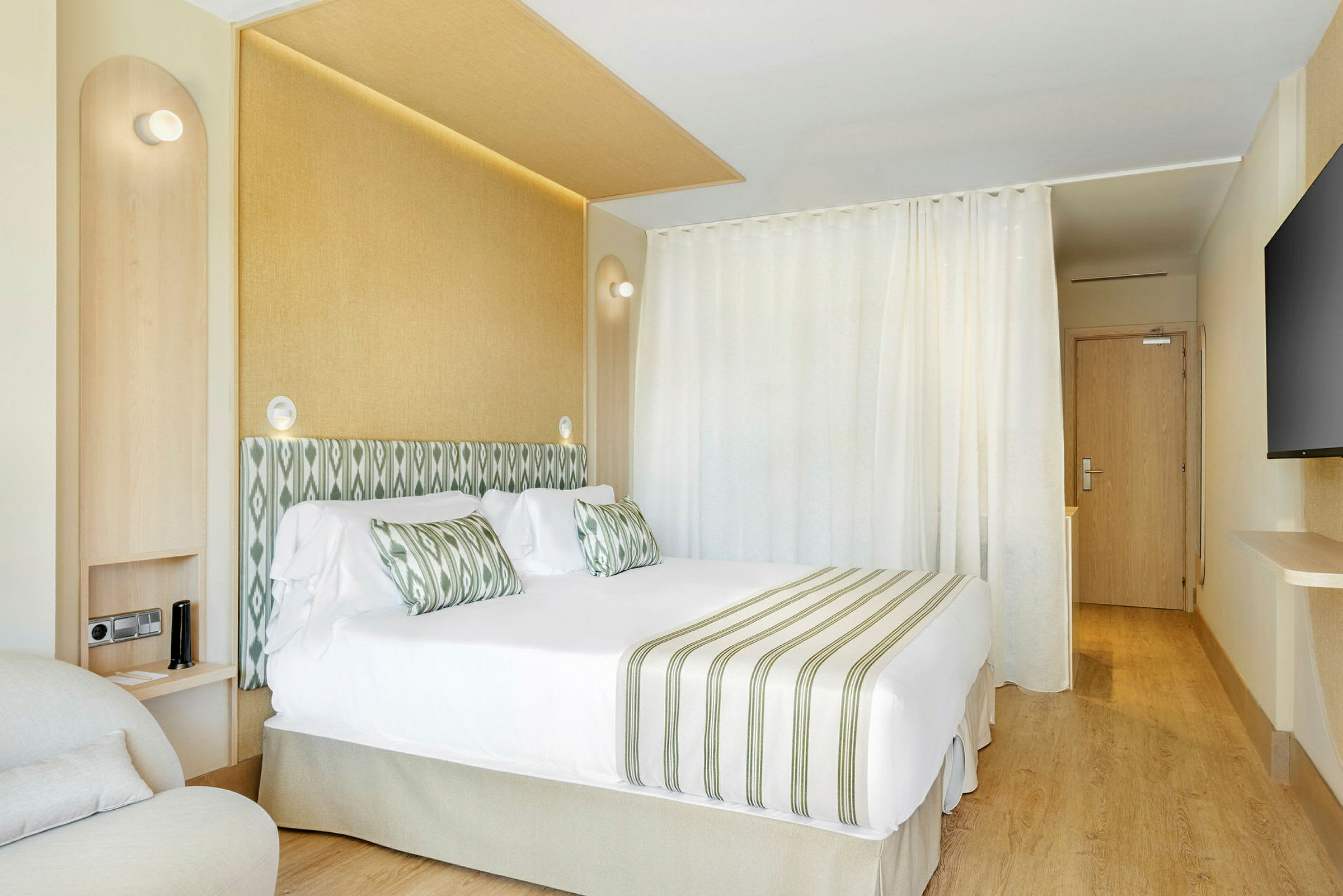 Hotelværelse med dobbeltseng, grøn-hvid stribet indretning og lyse møbler. (AI-genereret tekst)