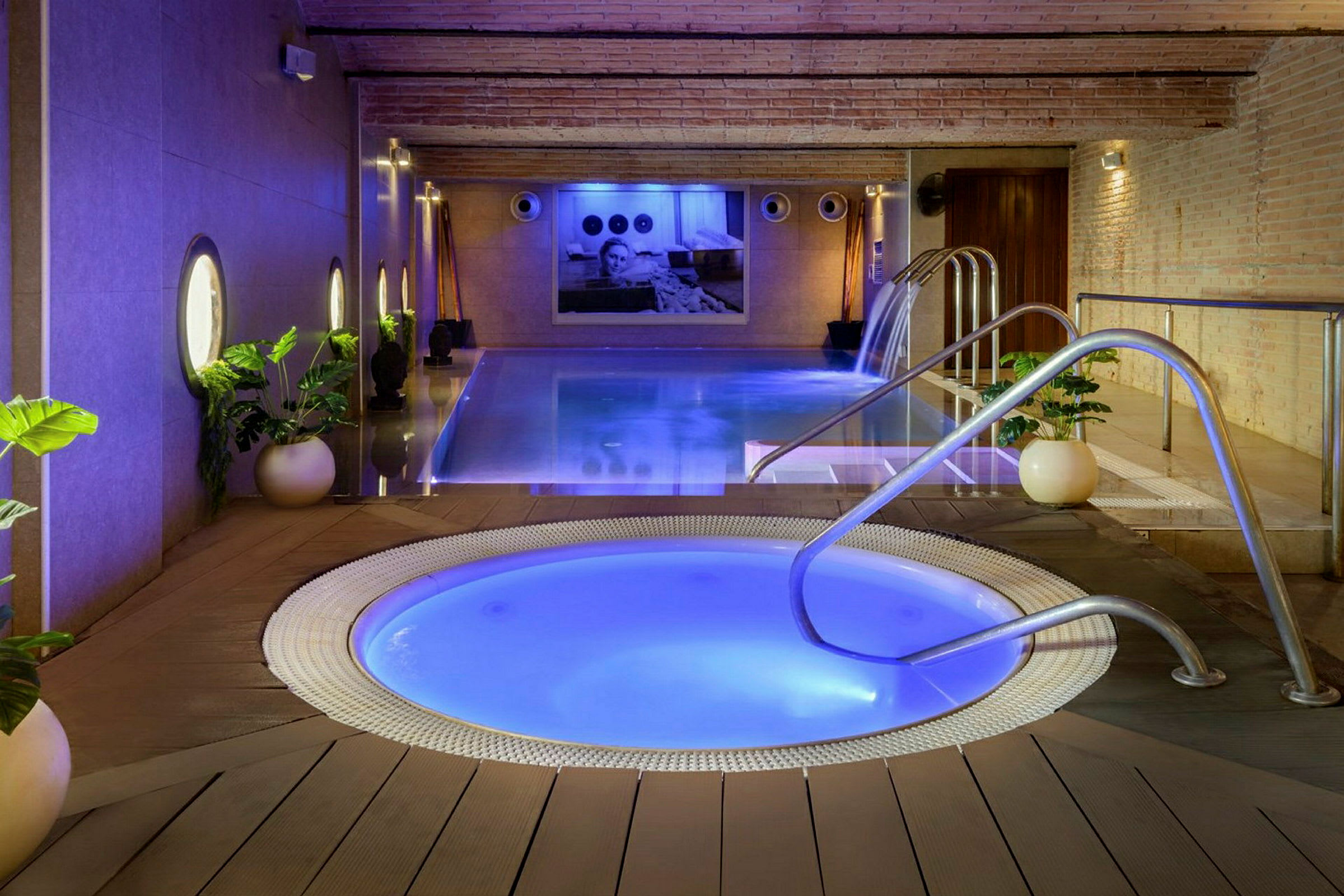 Billede af et afslappende pool- og jacuzzimiljø indendørs med planter og blød belysning. (AI-genereret tekst)